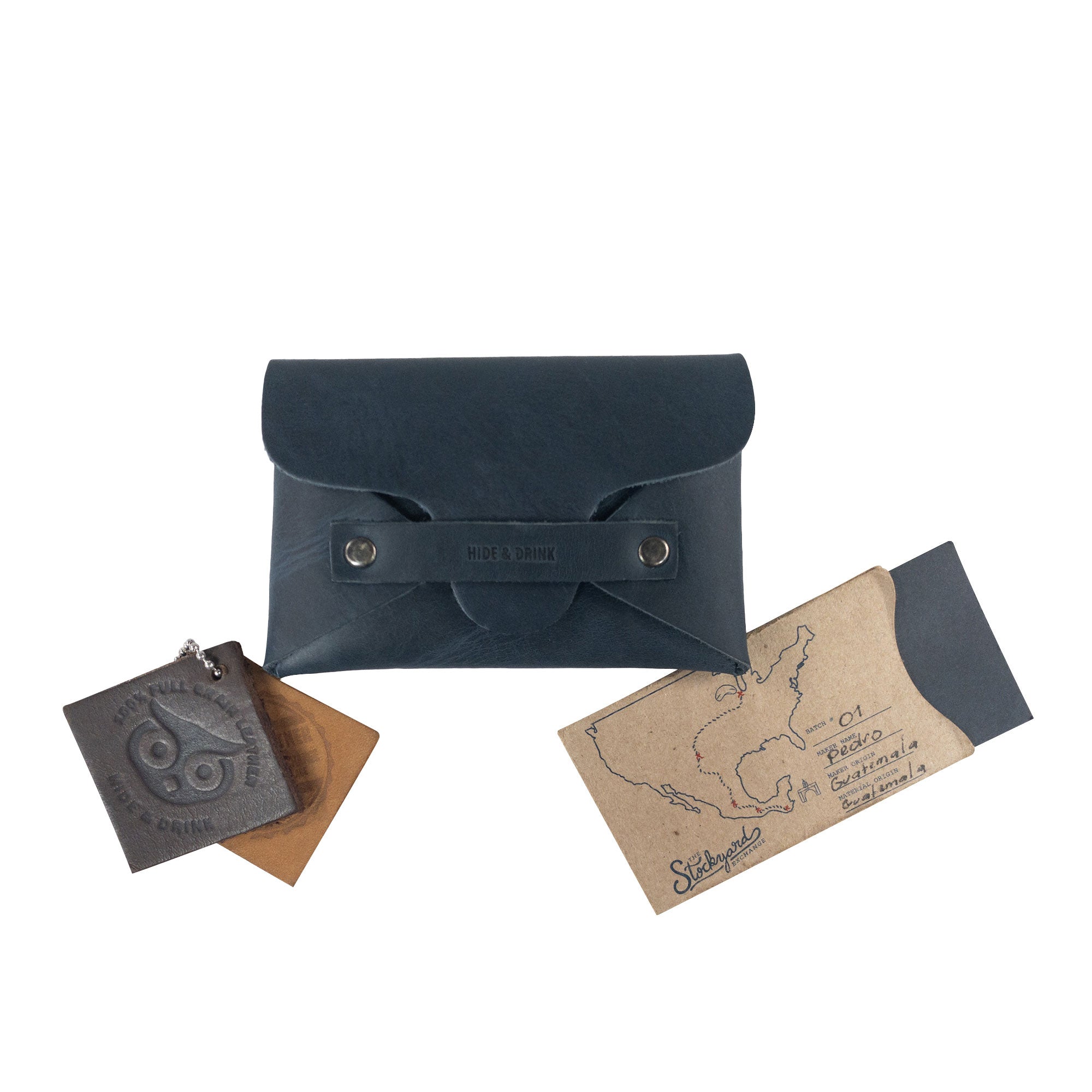 A Snapless Business Card Holder from Hide & Drink, elegantly situated with complementary accessories. This vintage wallet is ideal for men and women and is crafted from luxurious Full Grain Leather, acting as a sturdy pouch and money organizer, representing traditional artisan craftsmanship from La Antigua Guatemala and Oaxaca Mexico.