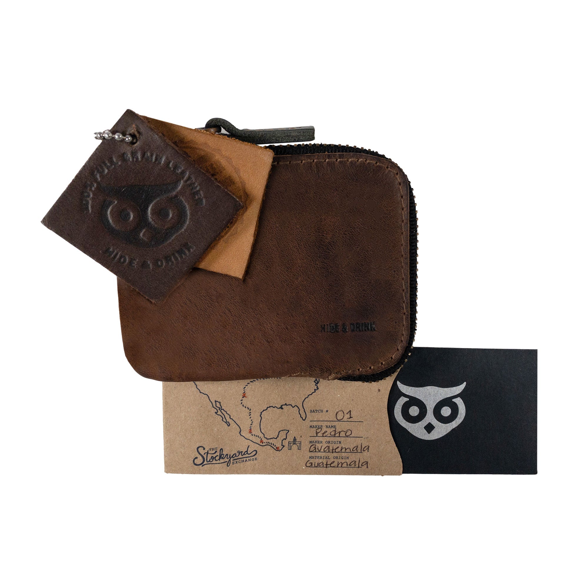 A Hide & Drink Card Pocket Wallet with tags demonstrating its authenticity. This zippered card wallet for men and women functions as a coin pouch and money holder, handcrafted from full grain leather in La Antigua Guatemala, illustrating the artisan's dedication and small batch production.
