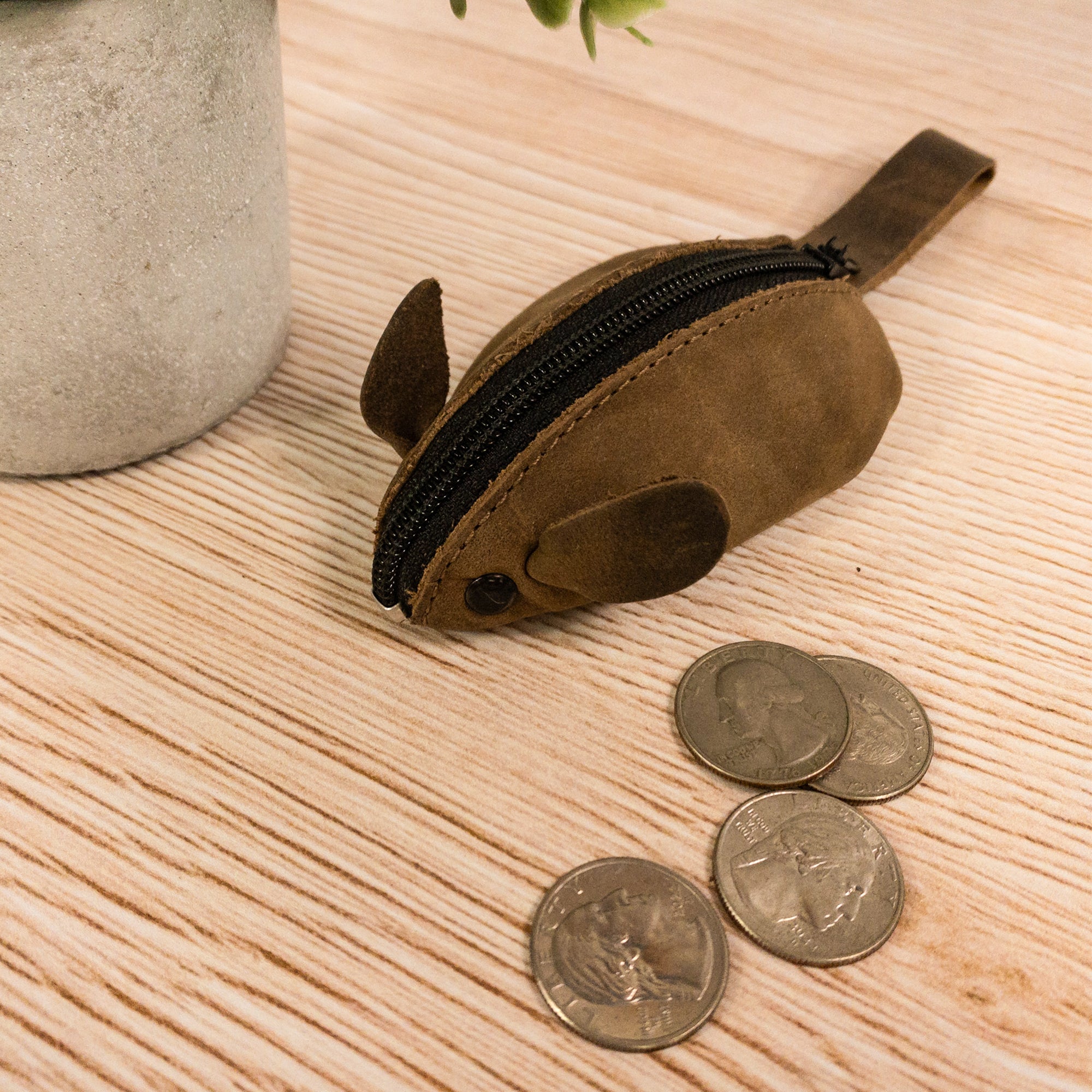 The Hide & Drink Mouse Coin Pouch sitting next to coins, showcasing its practical design and soft full grain leather material. This mouse-shaped change pouch is an artisan-made product from La Antigua Guatemala, serving as a stylish pocket case for coins and a perfect travel accessory.