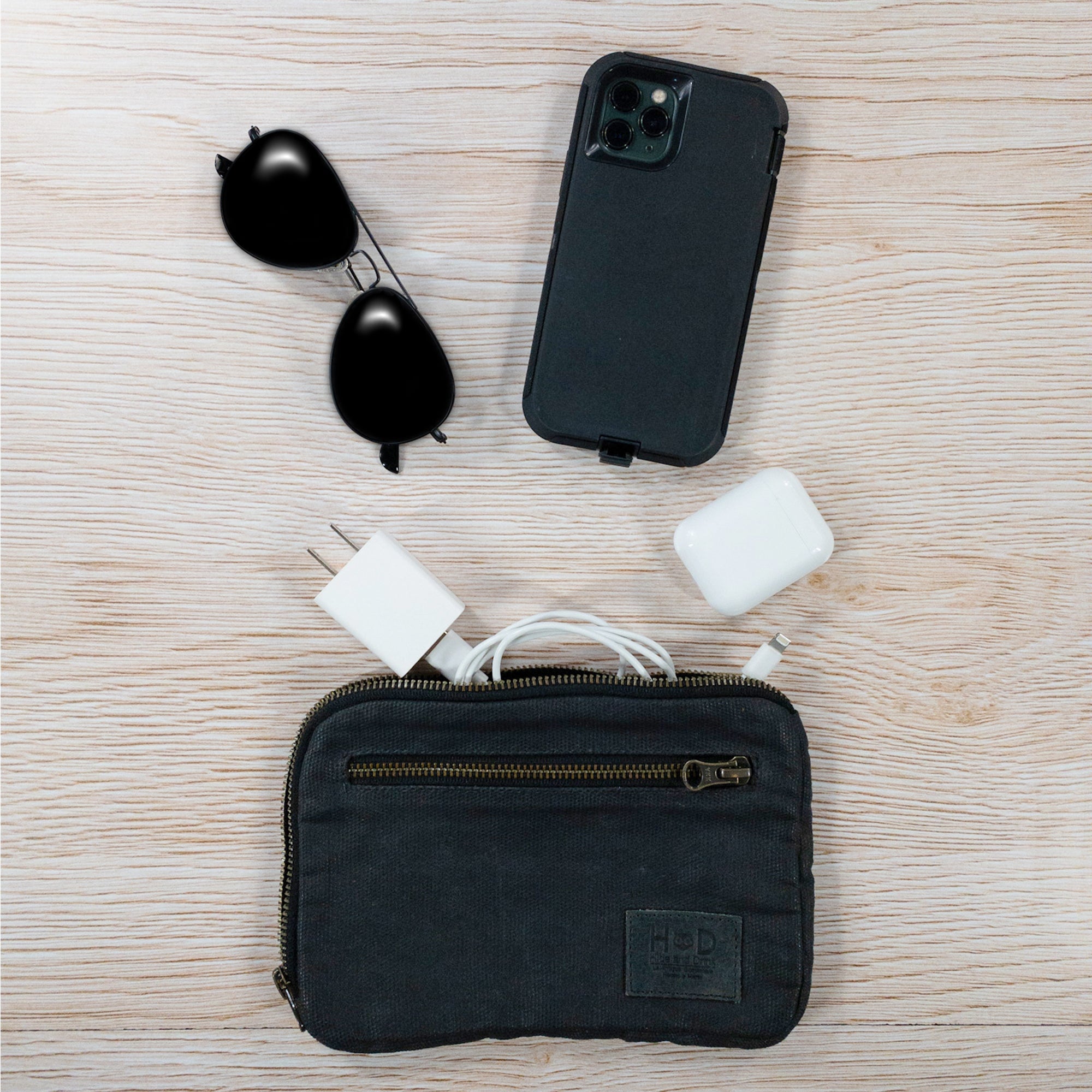Hide & Drink's Zipper Gear Pouch with personal items, showcasing its organized design and water resistant waxed canvas durability, ideal as a travel bag.