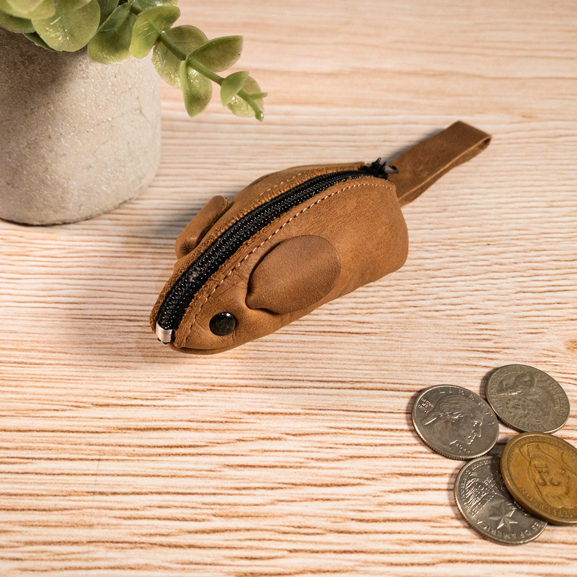 Hide & Drink's Mouse Coin Pouch placed among loose change, showcasing its functionality. This charming Mouse-Shaped Coin Pouch is a practical change pouch, perfect for on-the-go use, crafted with care and attention to detail.