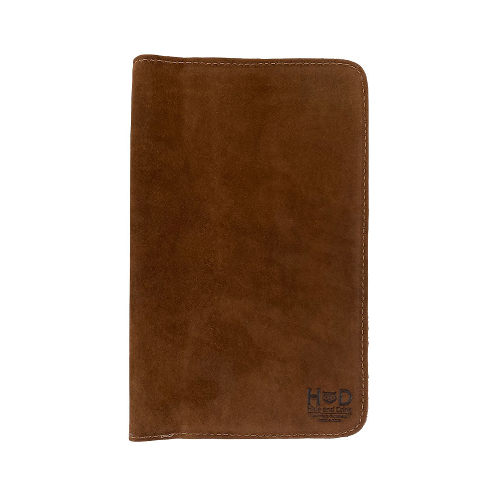 View of a closed brown Journal Cover for Moleskine Cahier L (5 x 8.25 in.) by Hide & Drink. This rustic protector is handcrafted from full grain leather, making it ideal for large size (5 x 8.25 in.) notebooks, showcasing artisan quality.