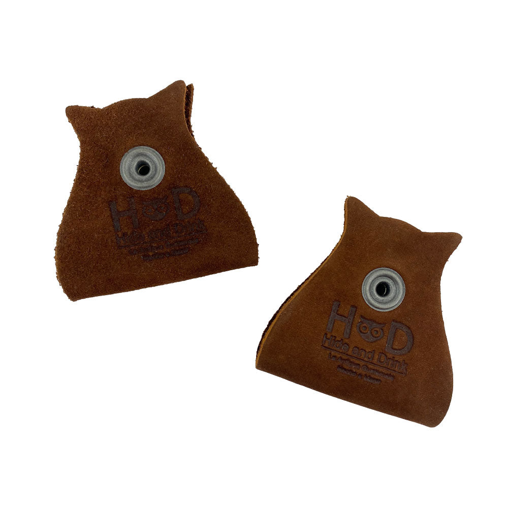 Stylish Owl Shaped Cord Keeper (2-Pack) by Hide & Drink showcasing two cord keepers embossed with the brand logo on genuine leather. Owl Shaped Cord Keeper (Cord Clam) 2-Pack. Full Grain Leather, StockyardX, Small Batch Production, Hand Cut, Hand Sewn, Fire Branded, Artisan, Handmade in La Antigua Guatemala & Oaxaca Mexico.