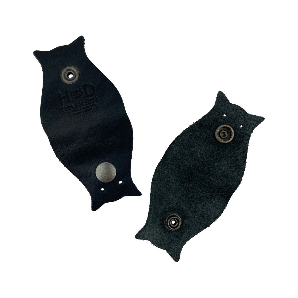 Owl Shaped Cord Keeper (2-Pack) by Hide & Drink featuring artisan-crafted black leather cord holders that emphasize quality and style in cable management. Owl Shaped Cord Keeper (Cord Clam) 2-Pack. Full Grain Leather, StockyardX, Small Batch Production, Hand Cut, Hand Sewn, Fire Branded, Artisan, Handmade in La Antigua Guatemala & Oaxaca Mexico.