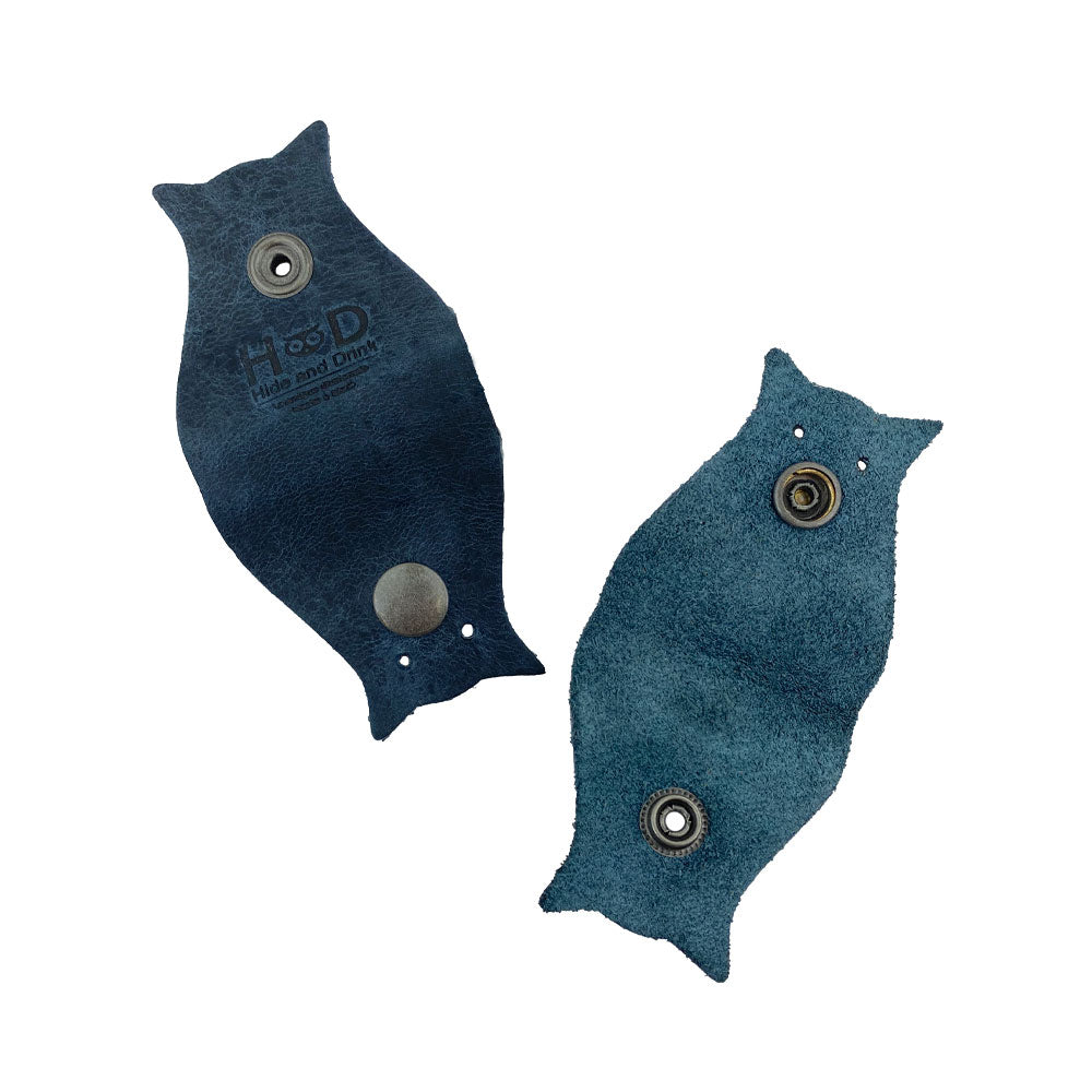 Owl Shaped Cord Keeper (2-Pack) by Hide & Drink featuring two artisan-made cord organizers in high-quality blue leather with snap closures. Owl Shaped Cord Keeper (Cord Clam) 2-Pack. Full Grain Leather, StockyardX, Small Batch Production, Hand Cut, Hand Sewn, Fire Branded, Artisan, Handmade in La Antigua Guatemala & Oaxaca Mexico.