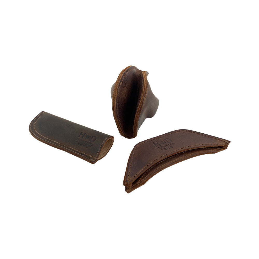An elegant arrangement of the 3 Rustic Hot Handle Holders by Hide & Drink, featuring the Panhandle, Side Kick, and Grip Mitt. Designed for effective use with cast iron pans, these pieces highlight the beauty of Full Grain Leather and are finely made through Small Batch Production, Hand Cut, and Hand Sewn by skilled artisans in La Antigua Guatemala & Oaxaca Mexico.