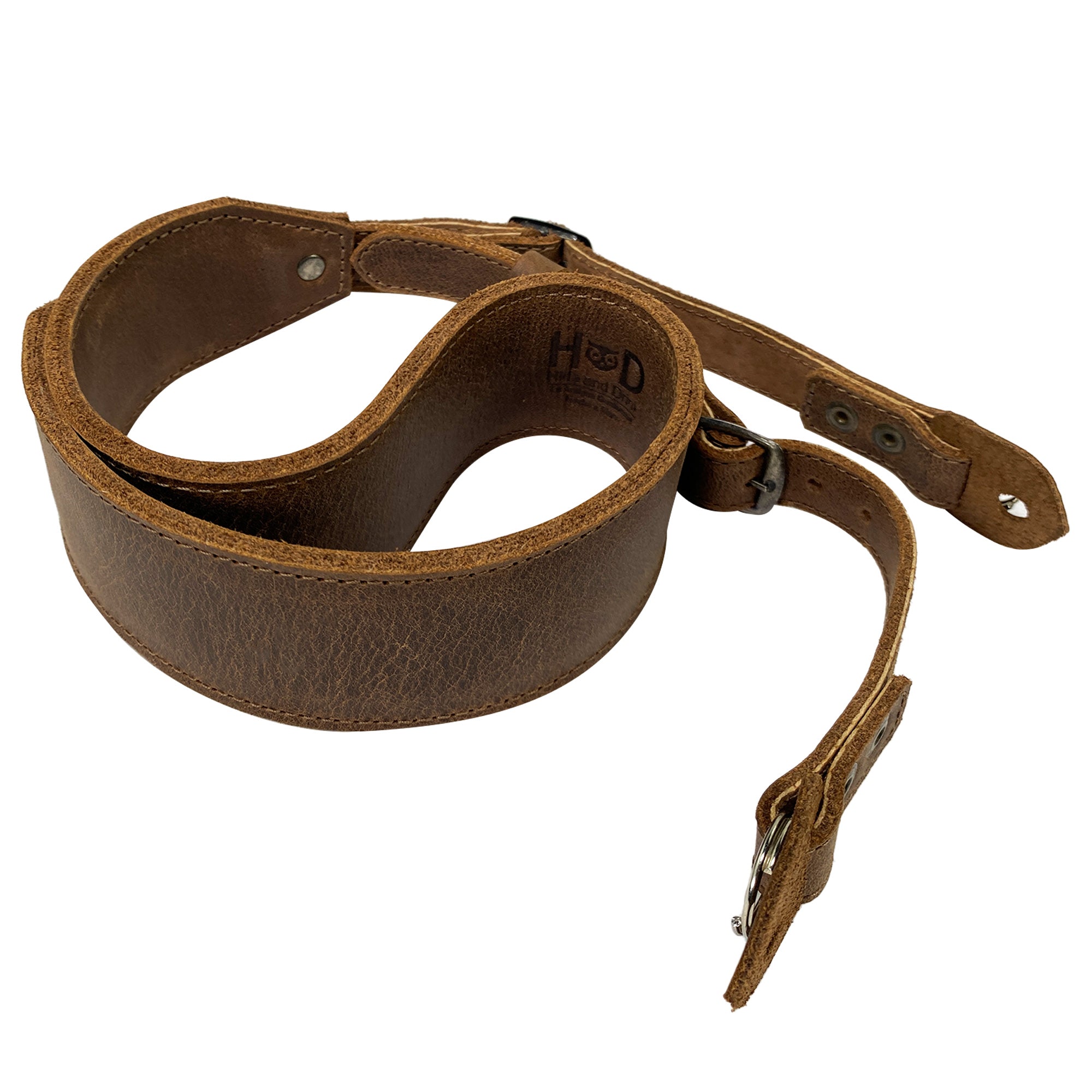 Hide & Drink Rustic Camera Strap displayed in a unique curled shape, exemplifying the quality of Full Grain Leather. This adjustable strap is designed for mirrorless and compact cameras, perfect as a thoughtful gift for photographers. StockyardX, Small Batch Production, Hand Cut, Hand Sewn, Fire Branded, Artisan, Handmade in La Antigua Guatemala & Oaxaca Mexico.