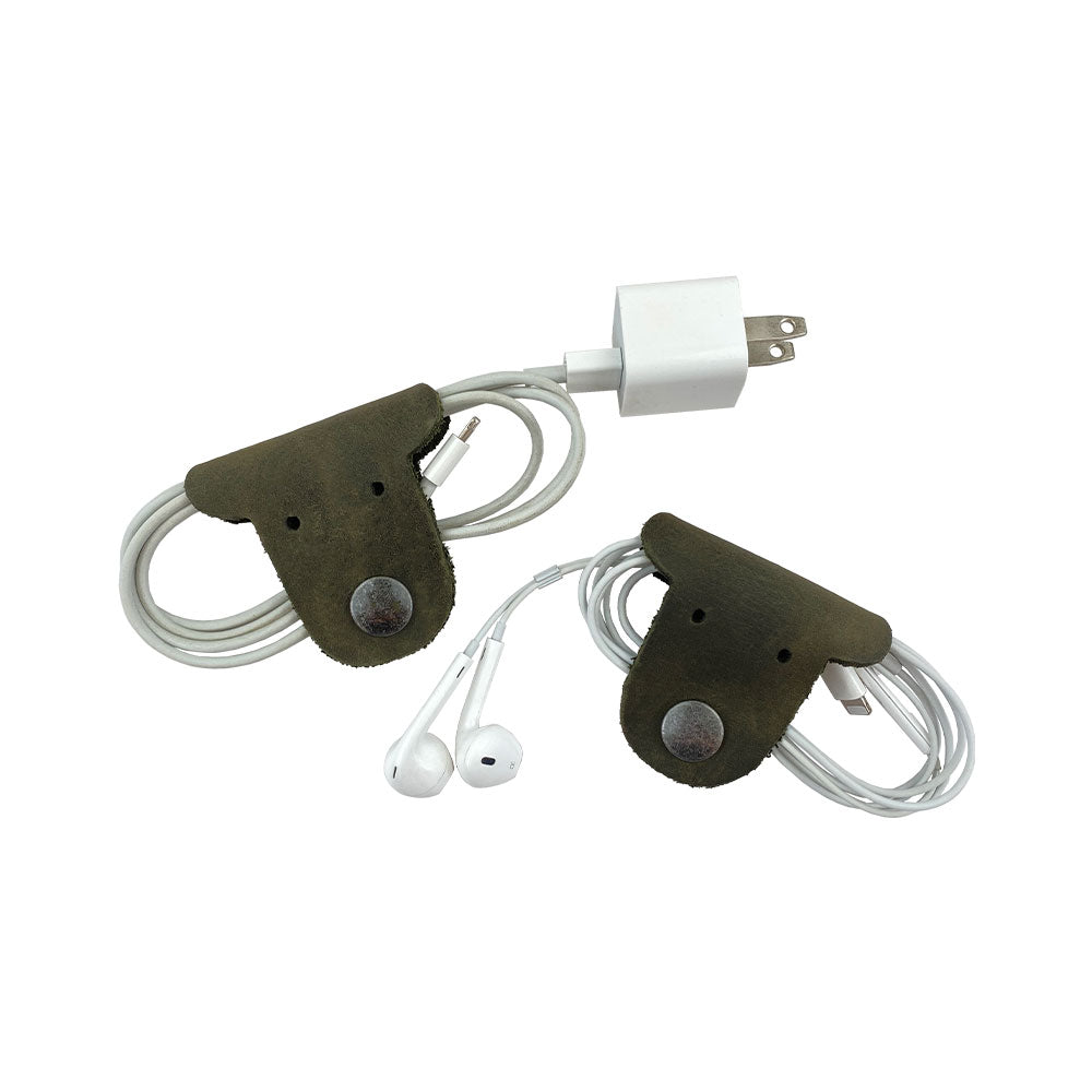 Two green Dog Shaped Cord Keepers holding a charging cord and earbuds, showcasing the practical and cute design from Hide & Drink. Dog Shaped Cord Keeper (Cord Clam) 2-Pack, Full Grain Leather, StockyardX, Small Batch Production, Hand Cut, Hand Sewn, Fire Branded, Artisan, Handmade in La Antigua Guatemala & Oaxaca Mexico.