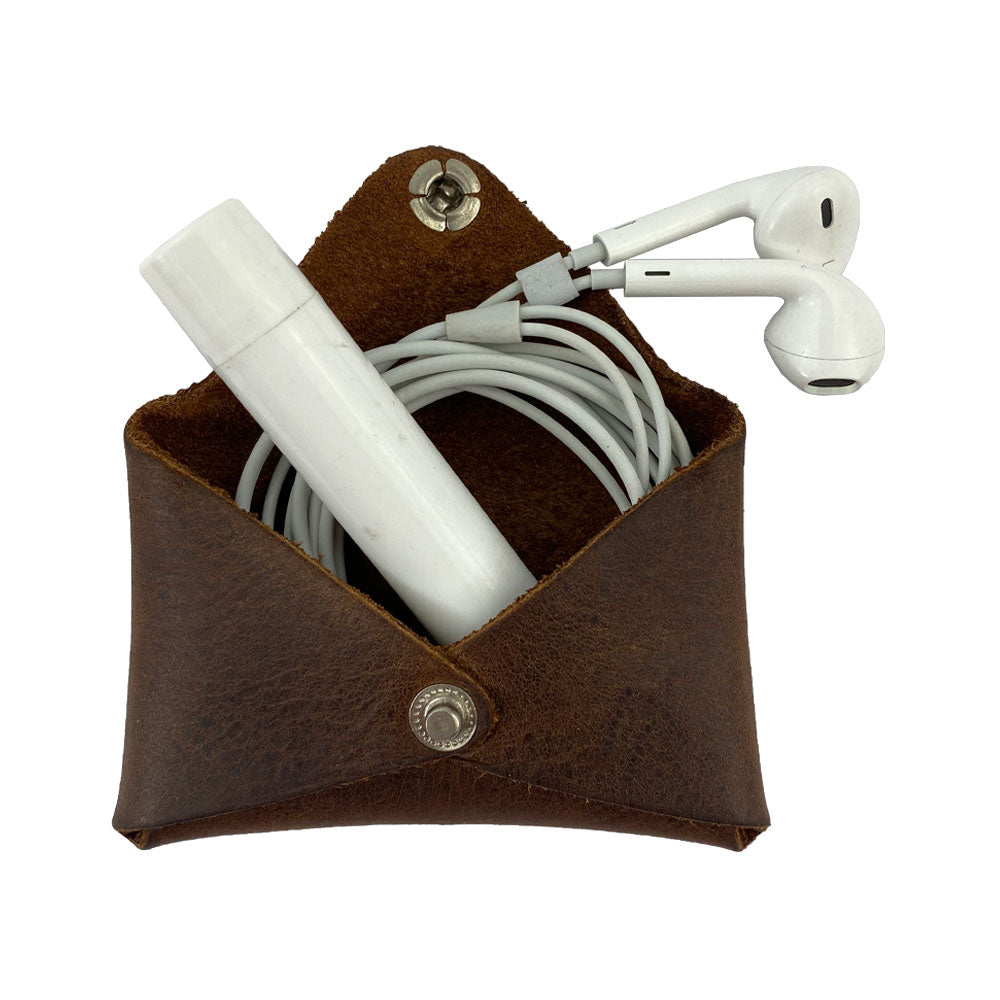 Hide & Drink Envelope Coin Case with earphones inside, illustrating its versatility and stylish design. This rustic leather item is crafted from full grain leather, showcasing artisan handmade skills from La Antigua Guatemala & Oaxaca Mexico.