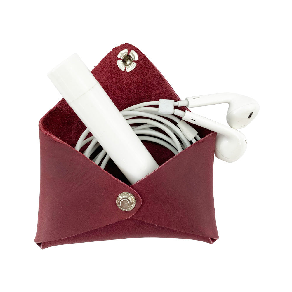 Hide & Drink Envelope Coin Case with earphones inside, demonstrating its stylish practicality. Crafted from full grain leather, this rustic leather product embodies artisan skills and is handmade in La Antigua Guatemala & Oaxaca Mexico.