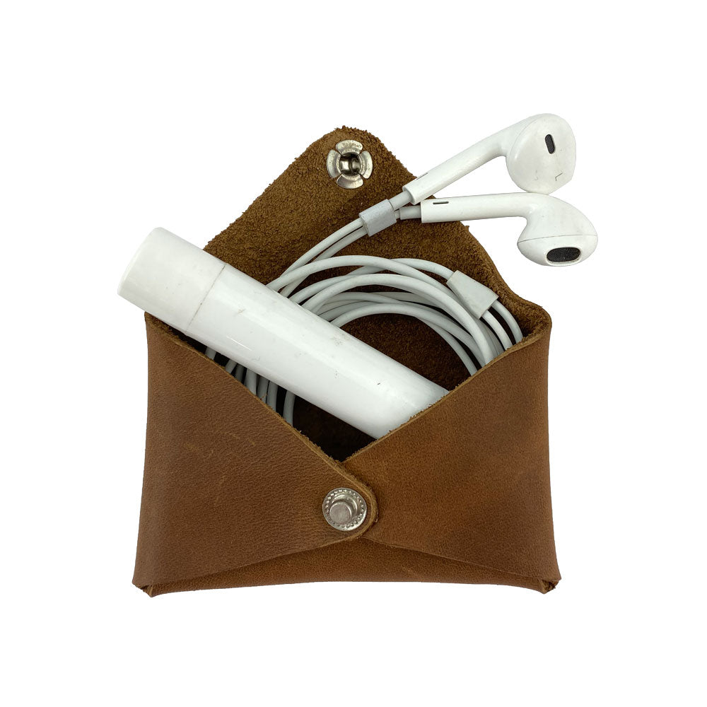 Hide & Drink Envelope Coin Case with earphones inside, emphasizing its versatile use. Crafted from full grain leather, this rustic leather piece represents artisan skills and handmade quality in La Antigua Guatemala & Oaxaca Mexico.