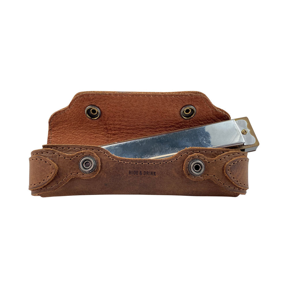 Harmonica Case by Hide & Drink with a harmonica inside, illustrating the perfect fit. Crafted from full grain leather, this vintage style protector is designed for musicians who appreciate handmade quality from La Antigua Guatemala. A stylish and functional accessory for your harmonica.