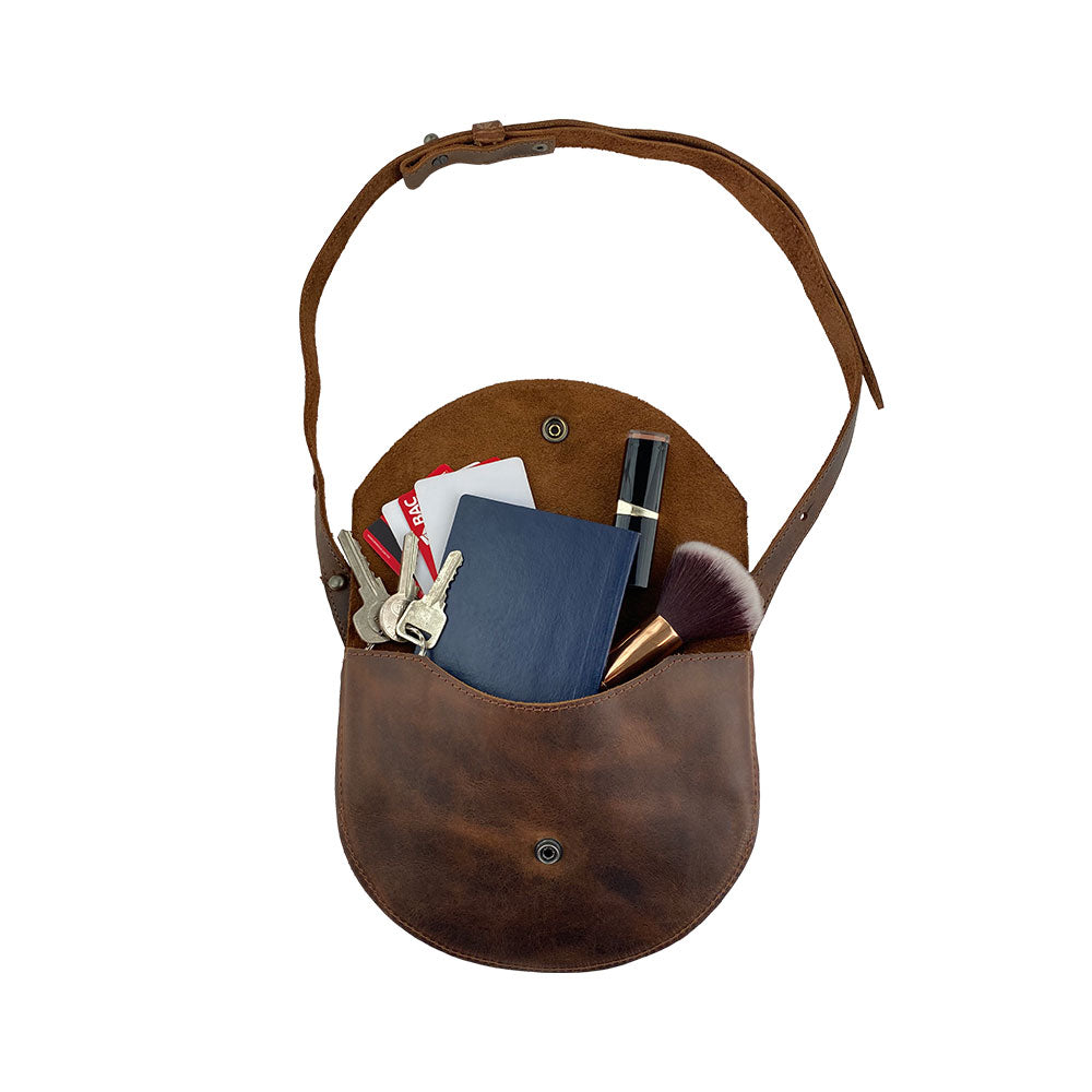 The Hide & Drink Hip and Shoulder Bag filled with essentials, showcasing its functional design and Full Grain Leather construction. Crafted through Small Batch Production, it is hand cut, hand sewn, and fire branded, offering an artisanal touch. Handmade in La Antigua Guatemala & Oaxaca Mexico.
