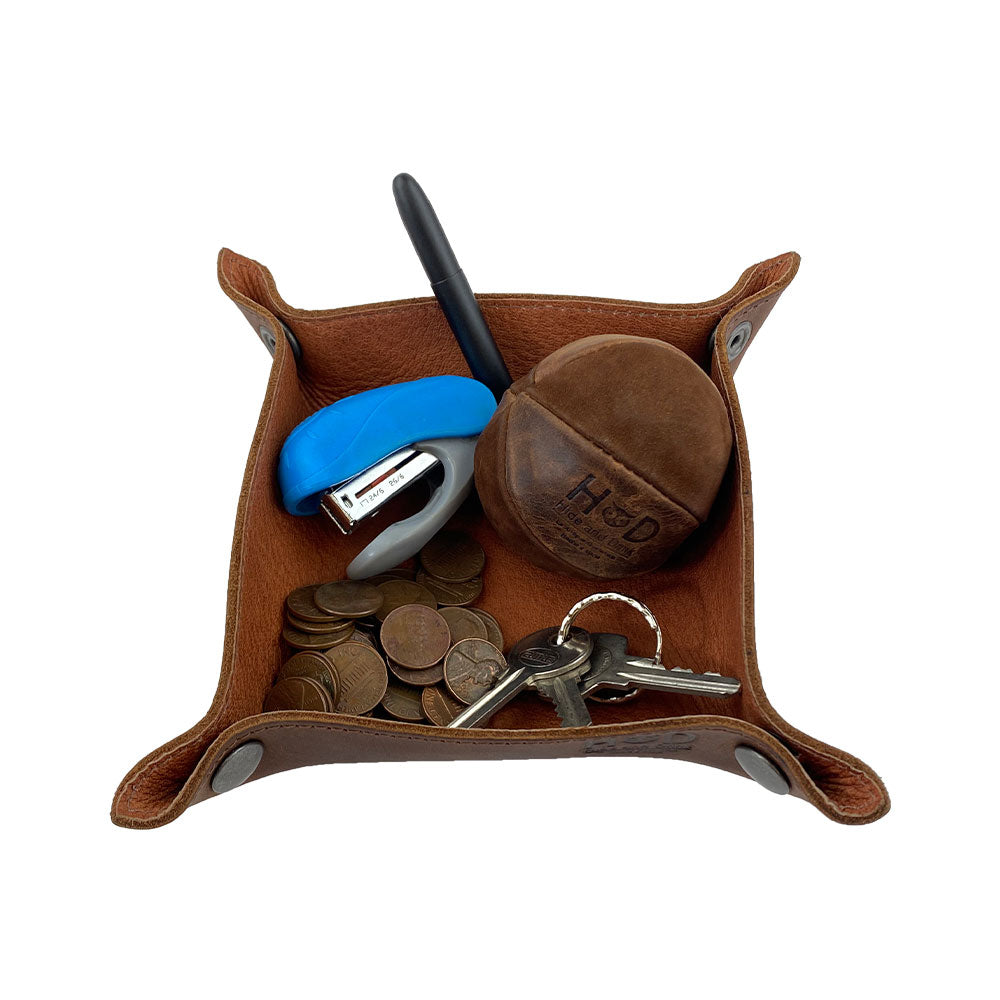 Functional Valet Tray with Sheep Skin by Hide & Drink filled with everyday items like keys, a pen, and coins. This elegant catchall is crafted from full grain leather and sheepskin, making it a stylish storage option for personal items. With artisan quality marked by hand cut, hand sewn details and fire branding, this tray exemplifies small batch craftsmanship tailored for home and travel essentials.