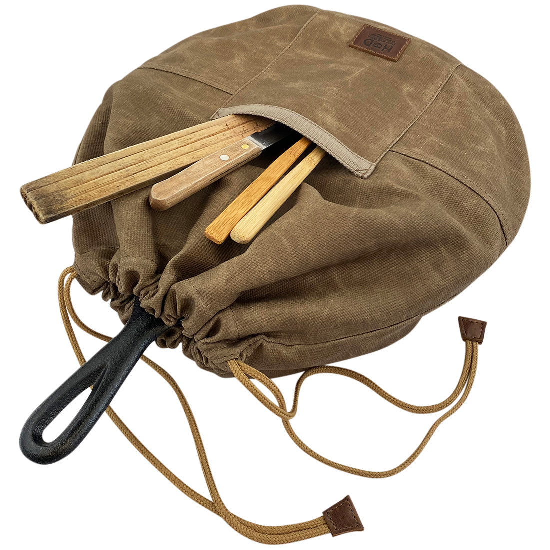 Skillet Bag Cover by Hide & Drink, featuring utensils stored in the front pocket. This handmade bag is perfect for a case for skillet without nonstick coating, crafted from enduring waxed canvas and showcasing expert craftsmanship from La Antigua Guatemala and Oaxaca Mexico.