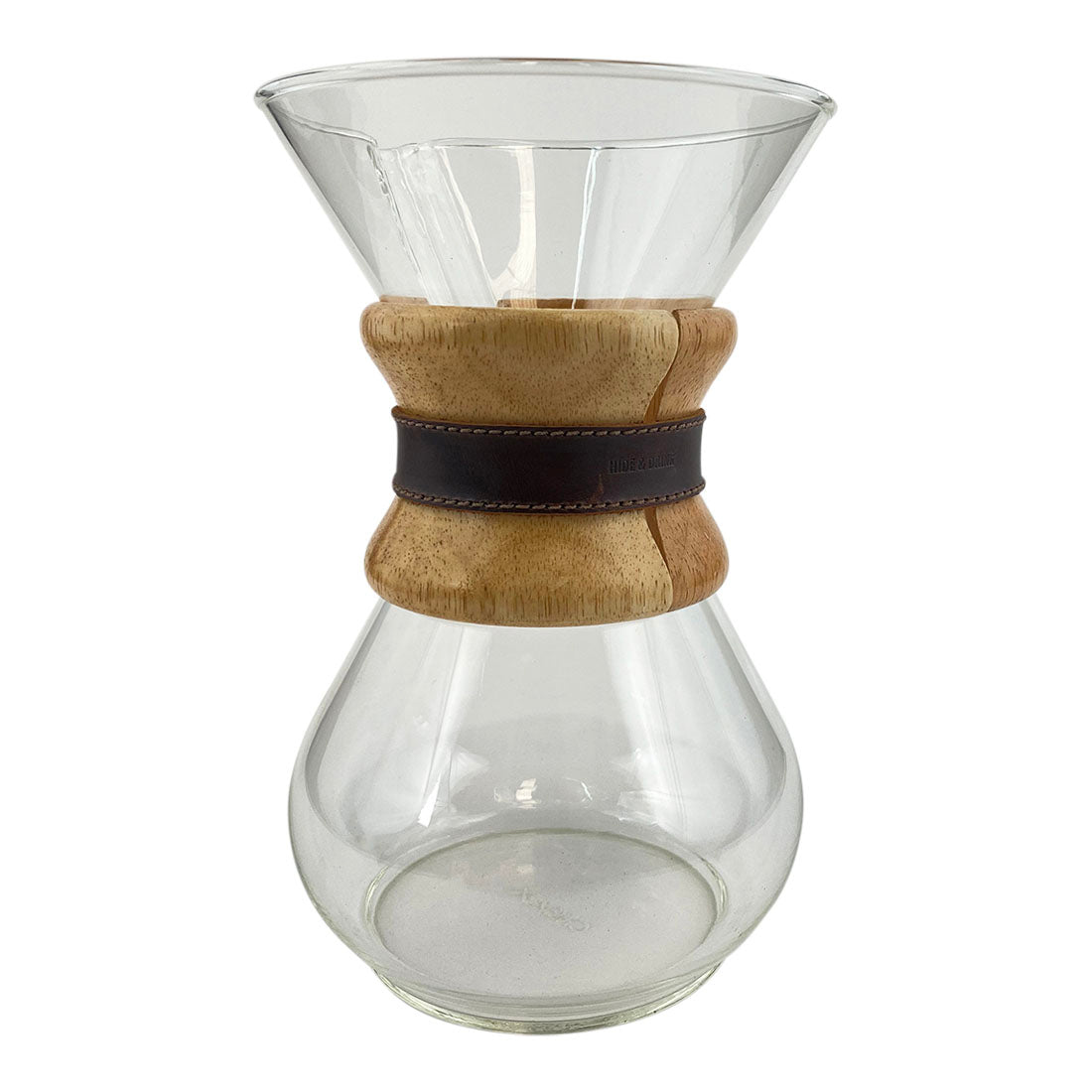 The Chemex coffee maker elegantly displayed with the Hide & Drink Chemex Strap Replacement. This strap adds a touch of durability and style while securely holding the collar. Pour Over Strap (2 Pack) Compatible with Chemex 6-Cup Glass, crafted from Full Grain Leather, showcasing artisan quality through small batch production, hand cut and hand sewn, fire branded in La Antigua Guatemala & Oaxaca Mexico.