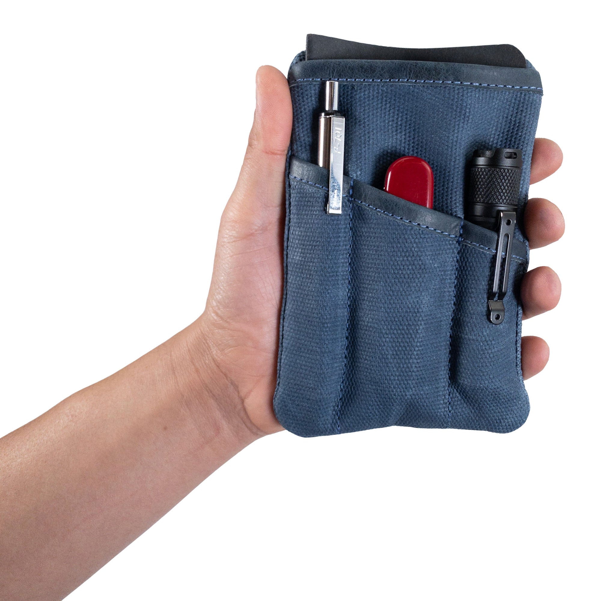 Person holding the green Multi-tool Pocket Pouch by Hide & Drink, demonstrating its usability as a knife holster and organizer.