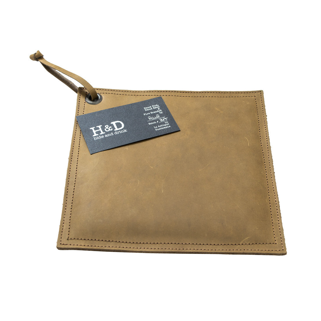 Hide & Drink Pot Pad in olive green leather showcased next to cookware, ideal for protecting surfaces. This rustic hot pot pad is double-layered for added durability.