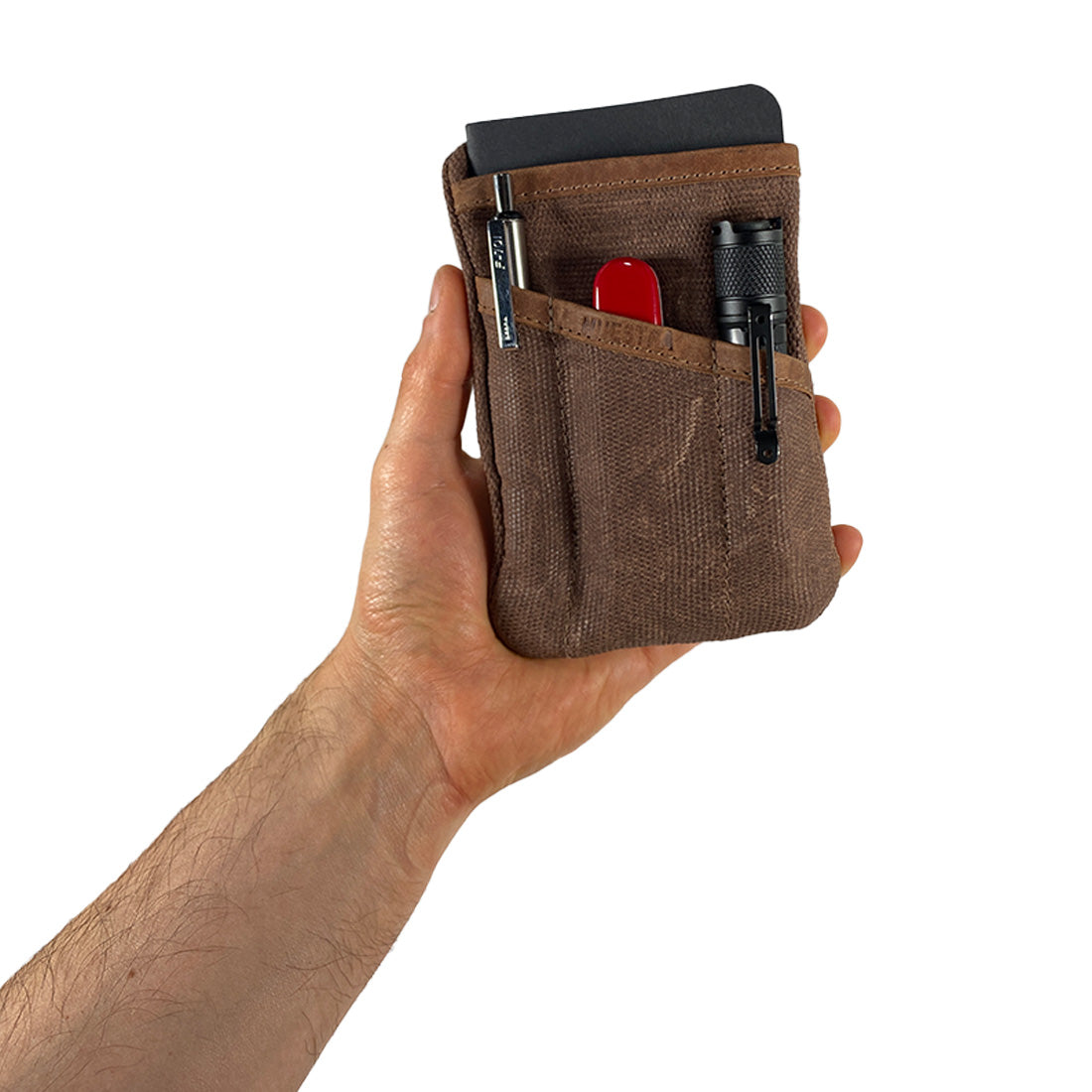 Person holding the brown Multi-tool Pocket Pouch by Hide & Drink, demonstrating its lightweight and ergonomic design for carrying essentials.