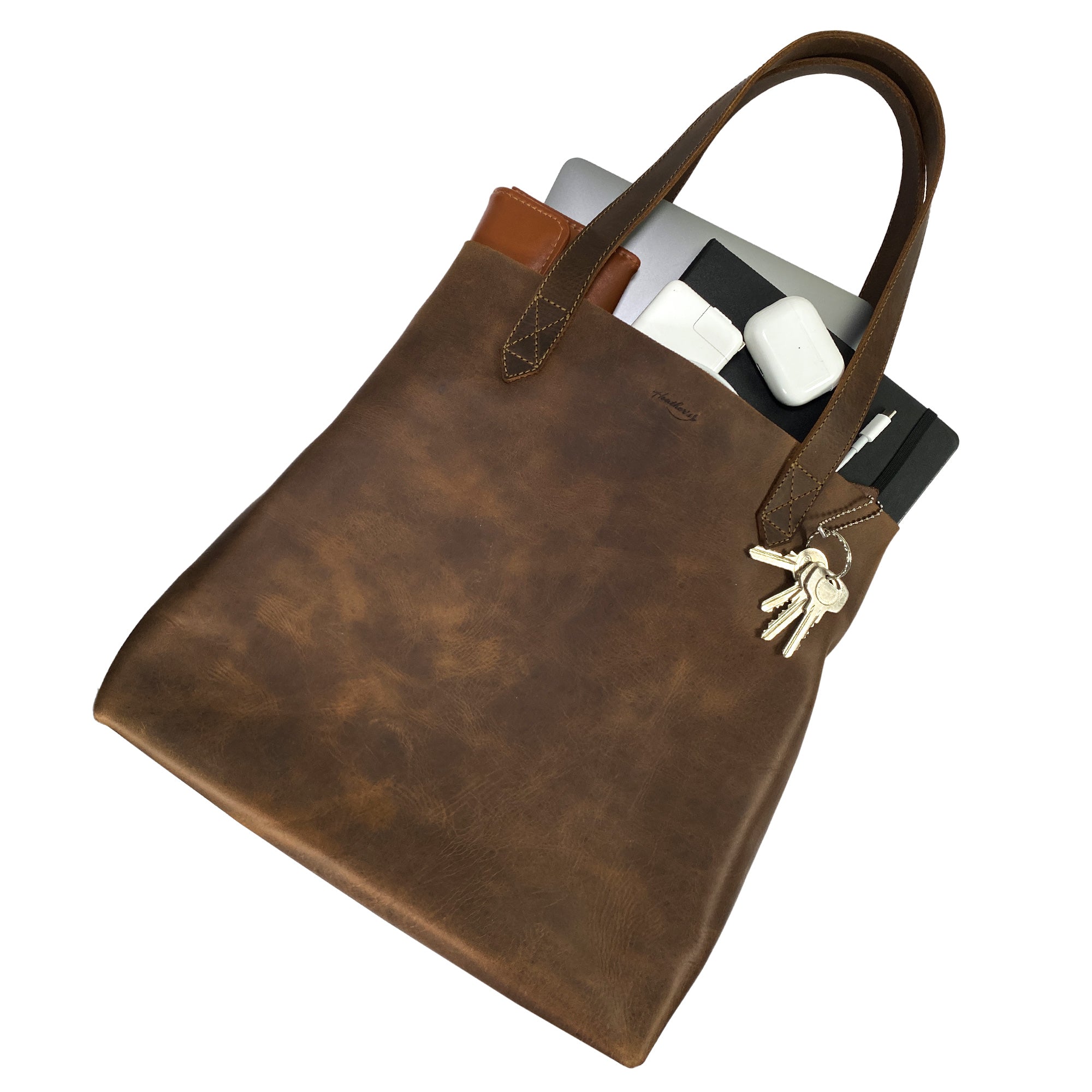 Heather's Classic Tote Bag filled with essentials, exemplifying its spacious design and functionality. Crafted from full grain leather, this shoulder bag is ideal for travel and shopping while being an artisanal piece handmade in Oaxaca Mexico.