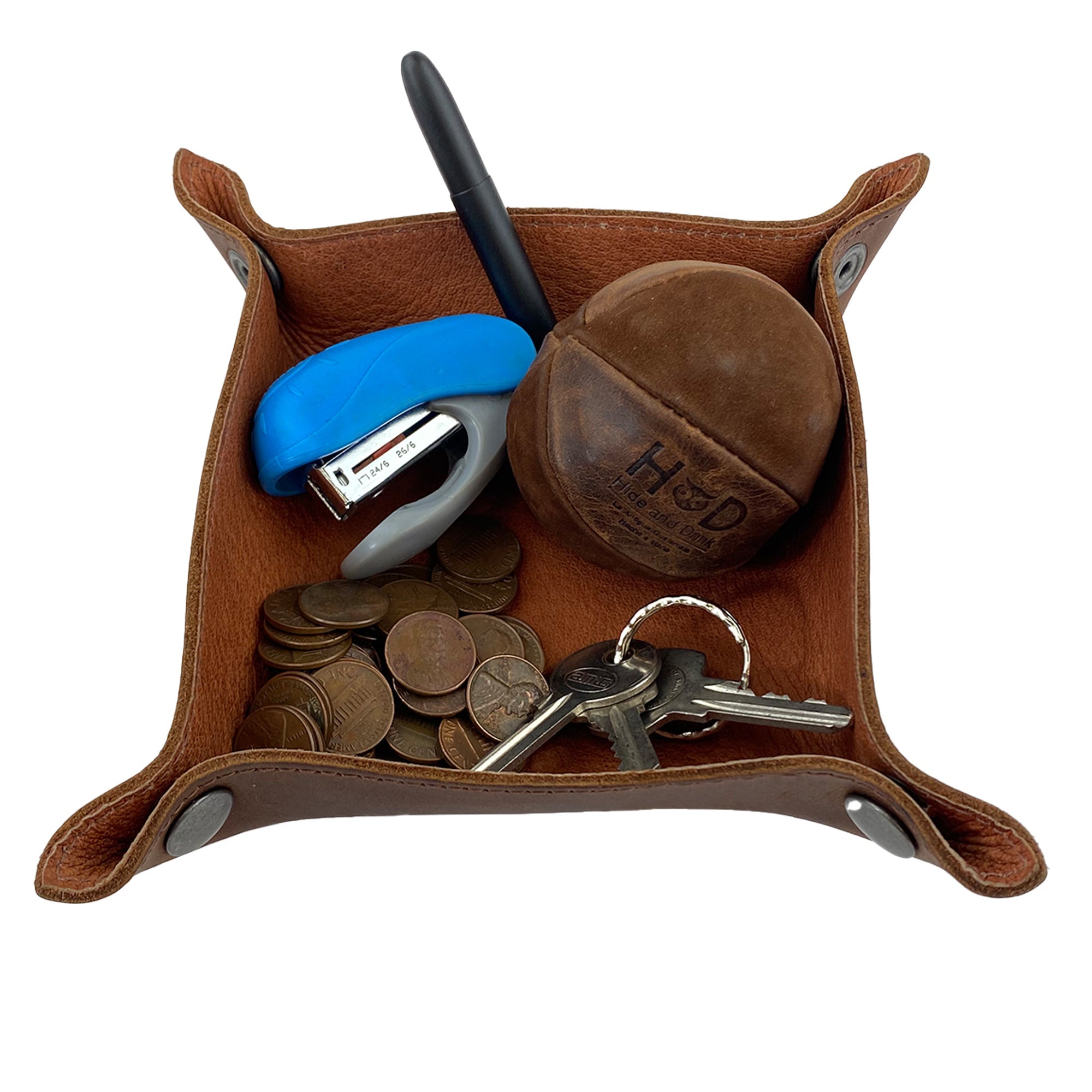 The Squared Catchall by Leather At Home filled with coins, keys, and a pen, demonstrating its perfect utility as a storage valet for everyday items. Crafted from full grain leather, it represents the essence of artisan handmade quality.