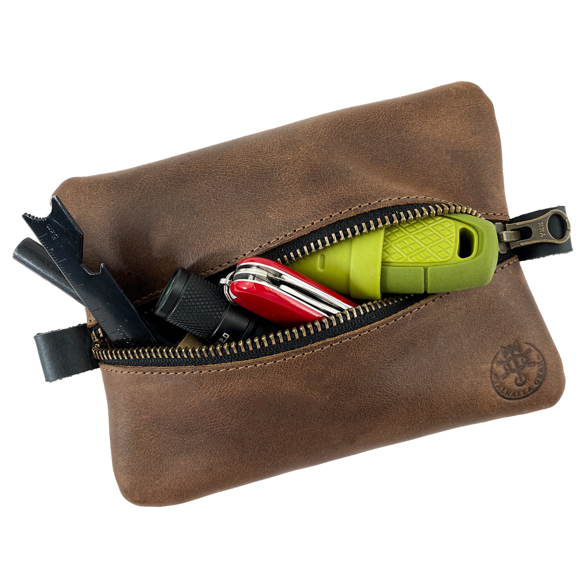 The EDC Zippered Pouch by Valhalla Gear filled with essential tools, demonstrating its practicality. This handmade accessory bag from full grain leather is perfect for organizing small personal items, showcasing exceptional artisan craftsmanship and small batch production from La Antigua Guatemala.