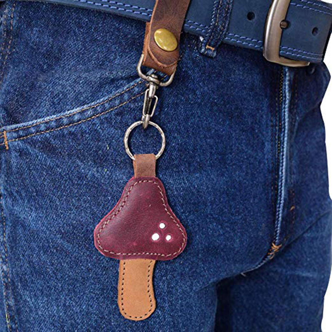 The Red Mushroom Keychain by Hide & Drink attached to a belt loop, illustrating its practicality and style. Made from durable Full Grain Leather, this unique accessory showcases StockyardX's dedication to small batch production. Hand cut, hand sewn, and fire branded, it's truly an artisan piece handmade in La Antigua Guatemala & Oaxaca Mexico.