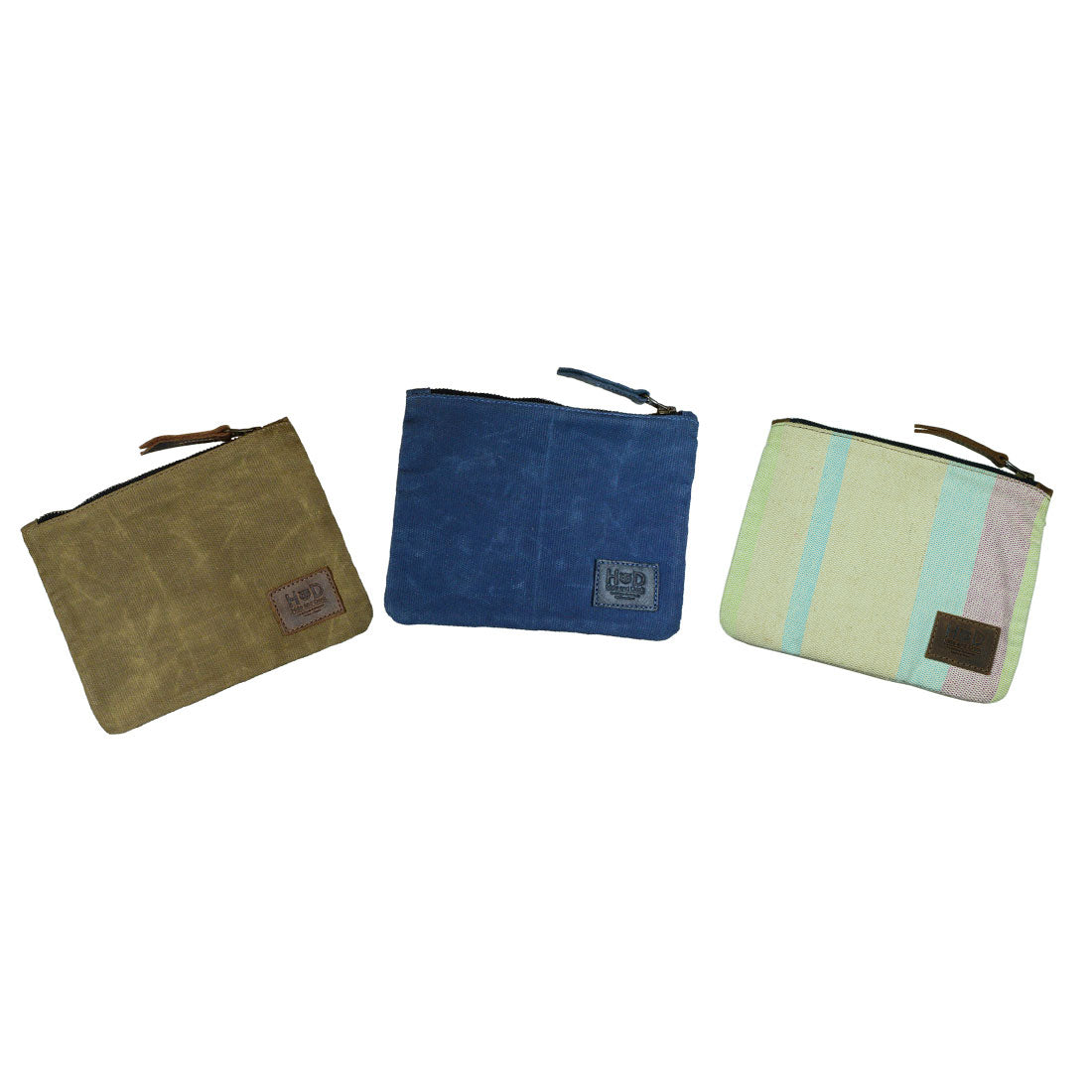 Three different Waxed Zippered Pouches from Hide & Drink in various colors, showcasing their versatility as multipurpose bags. These artisan-made Canvas Zippered Pouches are crafted with durable waxed canvas and full grain leather, embodying small batch production.
