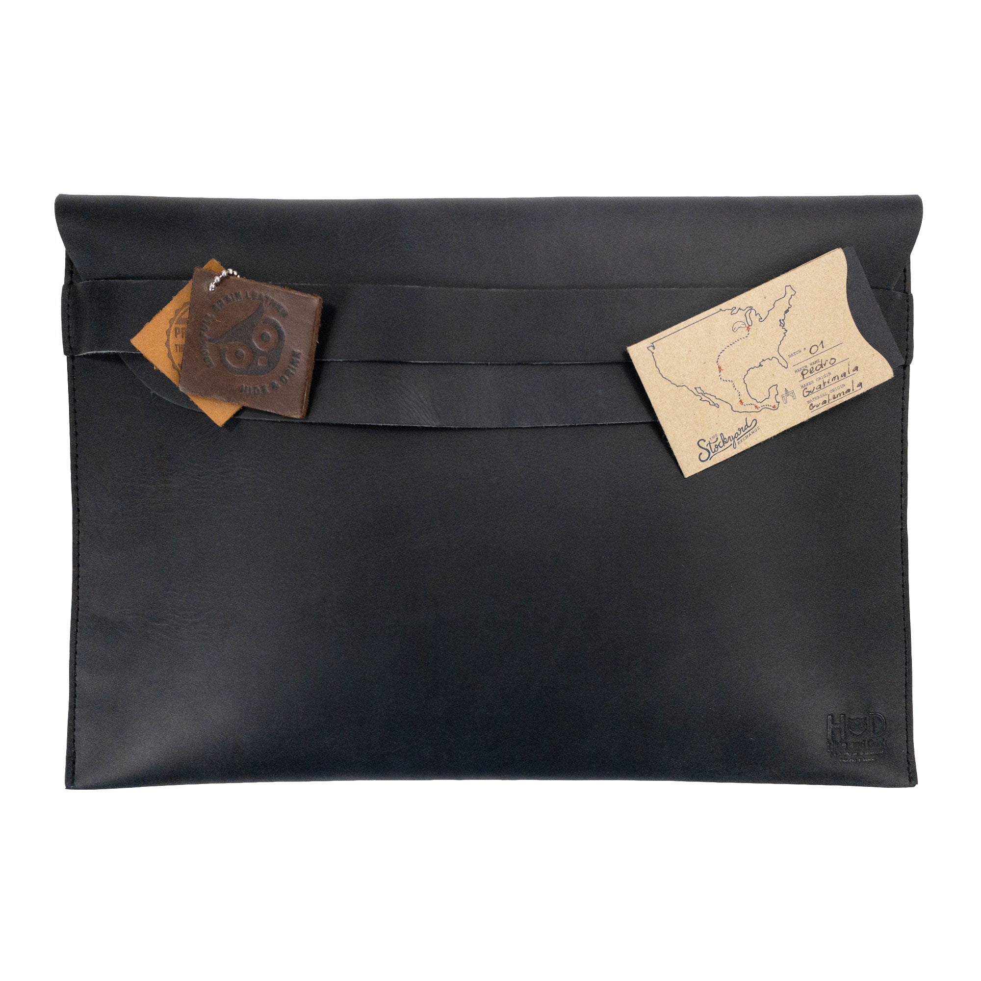 The back of the Hide & Drink MacBook Slim Case featuring a decorative leather tag, emphasizing its artisan touch. Ideal for MacBook Air/Pro 13 Inch with M1 Chip, this case is crafted from full grain leather with small batch production, showcasing unique handmade craftsmanship.