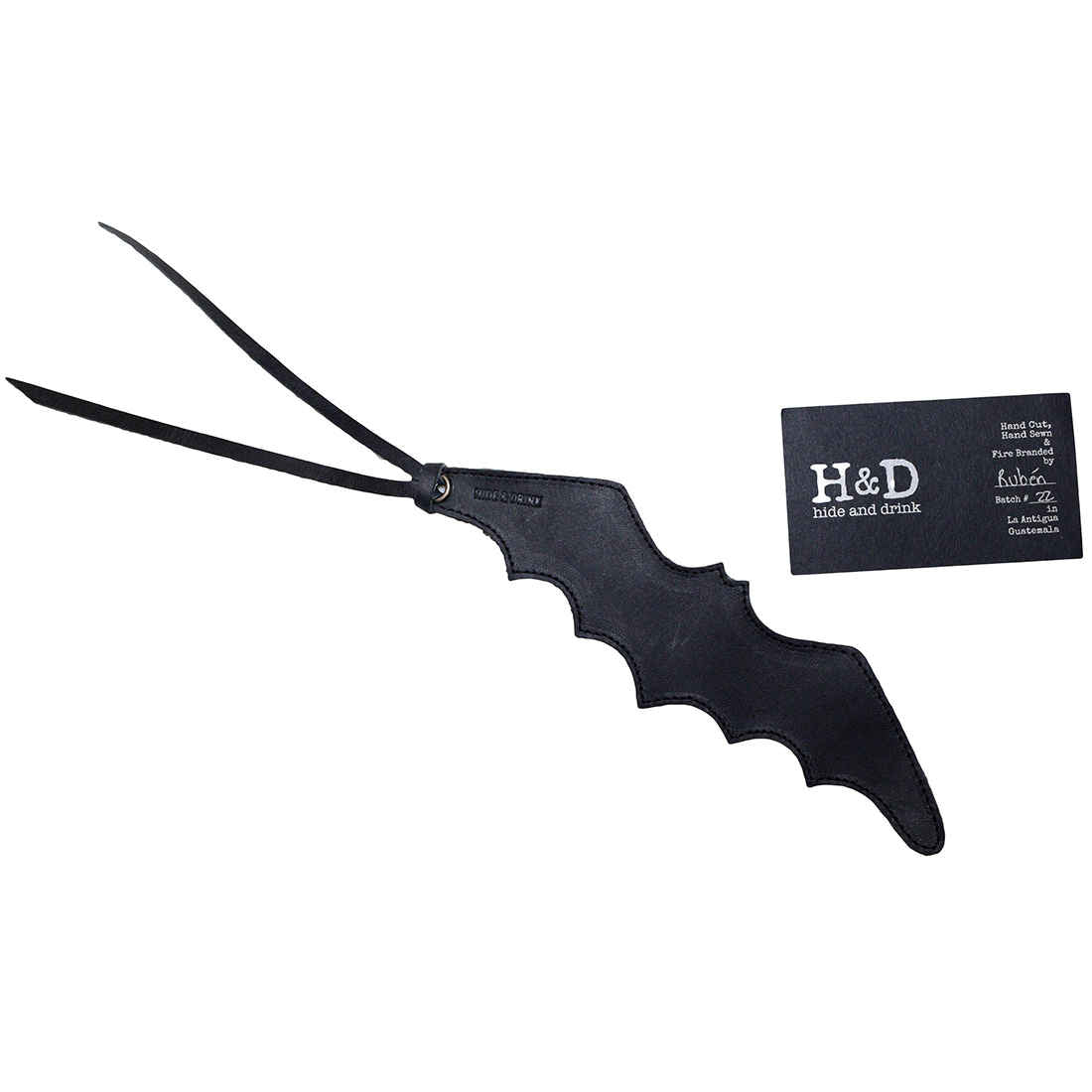 Hide & Drink Bat Bookmark alongside a business card, showing the artisanal quality of this unique bookmark. A must-have for superhero comic fans and book lovers, this handcrafted accessory is made from premium full grain leather.