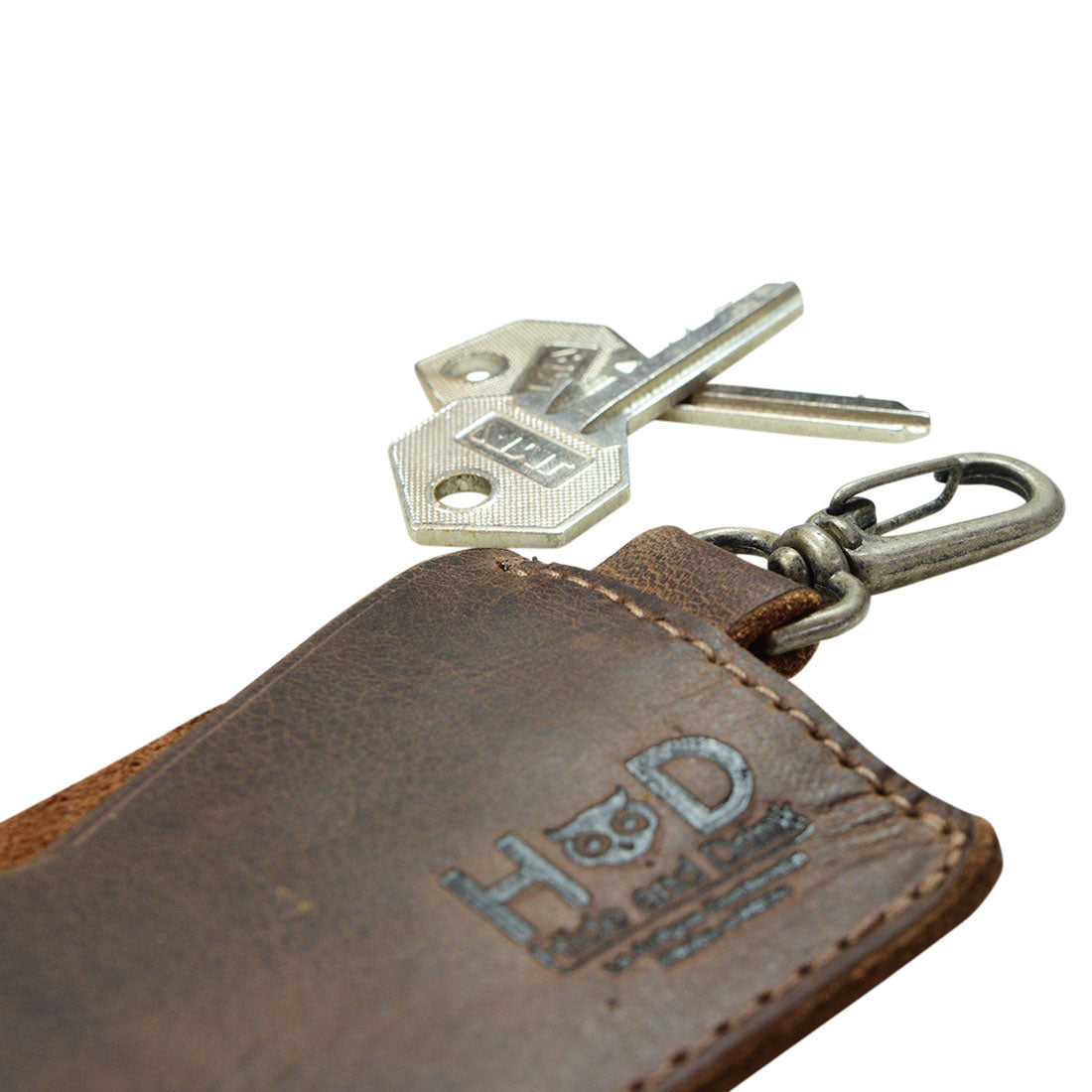 Close-up of Hide & Drink's Leather Card & Key Holder, featuring a key attachment. This organizer holds up to 4 cards and serves as a Keychain Organizer. Made from high-quality Full Grain Leather, it's not only functional but also a stylish accessory. Each piece is hand cut and hand sewn, with small batch production reflecting true craftsmanship from artisans in La Antigua Guatemala & Oaxaca Mexico.