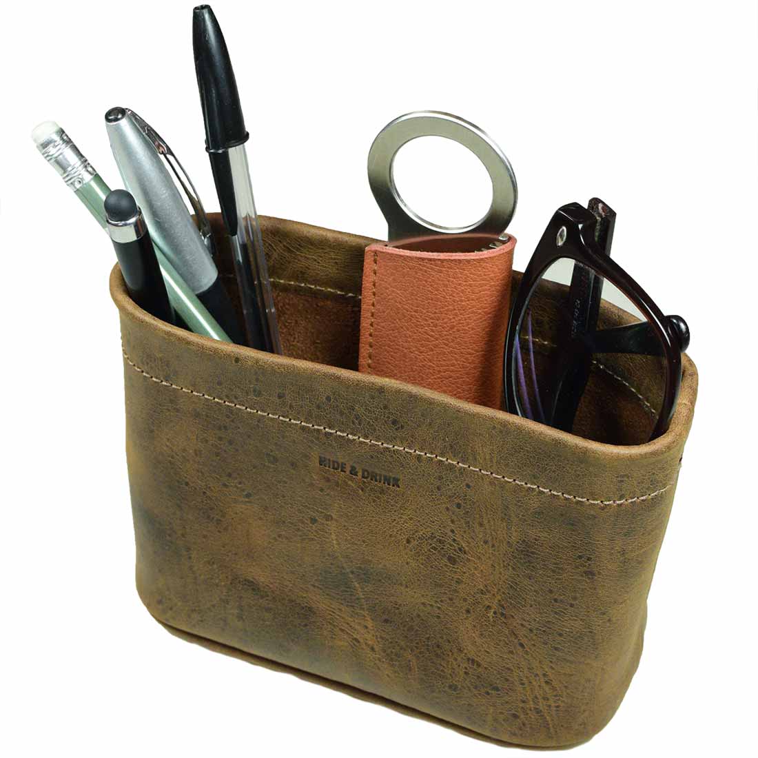 Close-up view of the Hide & Drink Desk Organizer Bag filled with office supplies, including a circular pen holder. This durable accessory made of Full Grain Leather emphasizes its small batch production and artisanal quality, handmade in La Antigua Guatemala & Oaxaca Mexico.