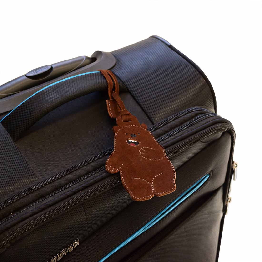 Bear Luggage Tag from Hide & Drink on a black suitcase, highlighting its playful character. This unique suitcase identifier and baggage label is made from full grain leather, reflecting the charm of small batch production. An artisan piece that is hand cut, hand sewn, and fire branded, handmade in La Antigua Guatemala & Oaxaca Mexico.