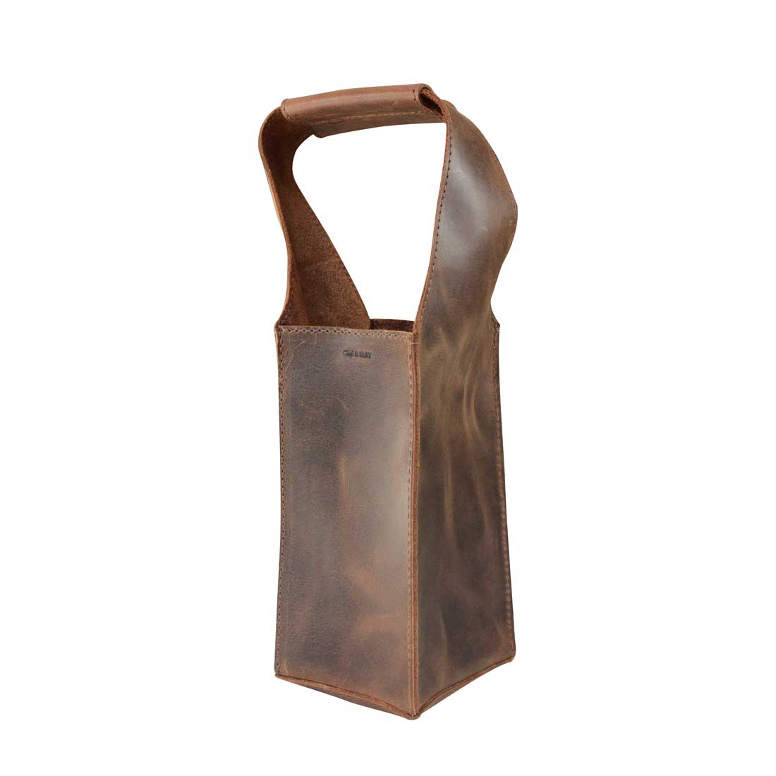 Side view of the Bottle Wine Carrier by Hide & Drink, highlighting its squared shape and durable handle. This rustic case is not just a Bordeaux bottle holder, but also a stylish carry-on pouch for picnic accessories. Crafted from full grain leather, it represents small batch production with hand cut and hand sewn excellence, fire branded in La Antigua Guatemala and Oaxaca Mexico.