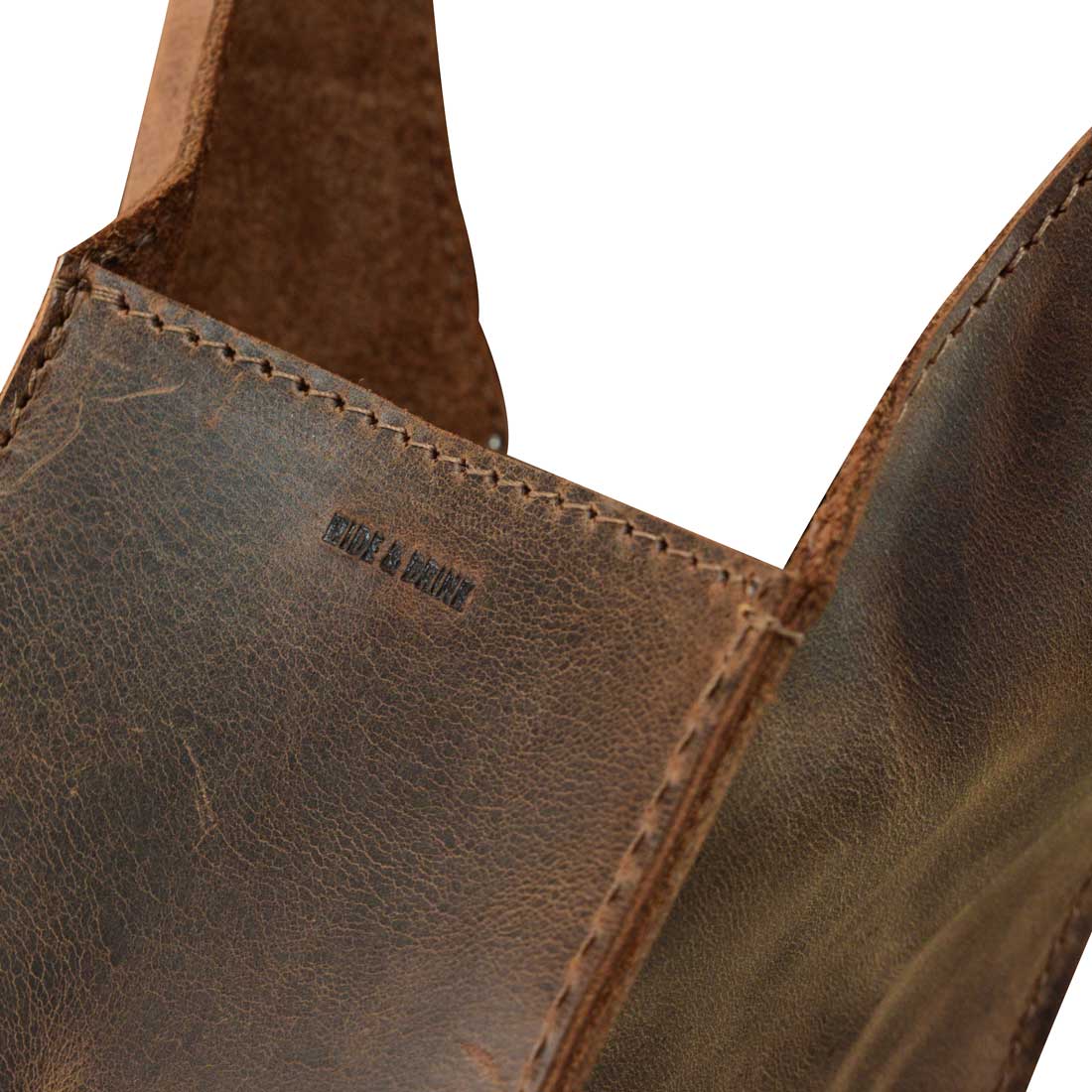 Close-up of the Bottle Wine Carrier by Hide & Drink, emphasizing the craftsmanship and full grain leather texture. This squared bottle wine carrier with handle is a perfect Bordeaux bottle holder and rustic case, ideal for picnic accessories. Handmade in La Antigua Guatemala and Oaxaca Mexico, it features small batch production and fire branded artisan details.