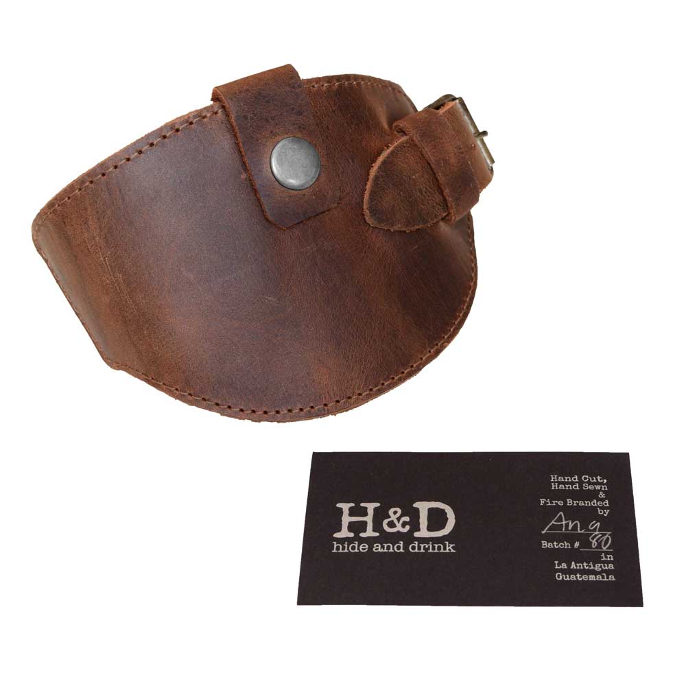 Motorcycle Boot Protector with buckle from Hide & Drink, paired with a business card highlighting its artisan roots. This sleek shoe cover features durable construction for shifter protection and is crafted from rustic full grain leather, reflecting the handmade quality from La Antigua Guatemala.