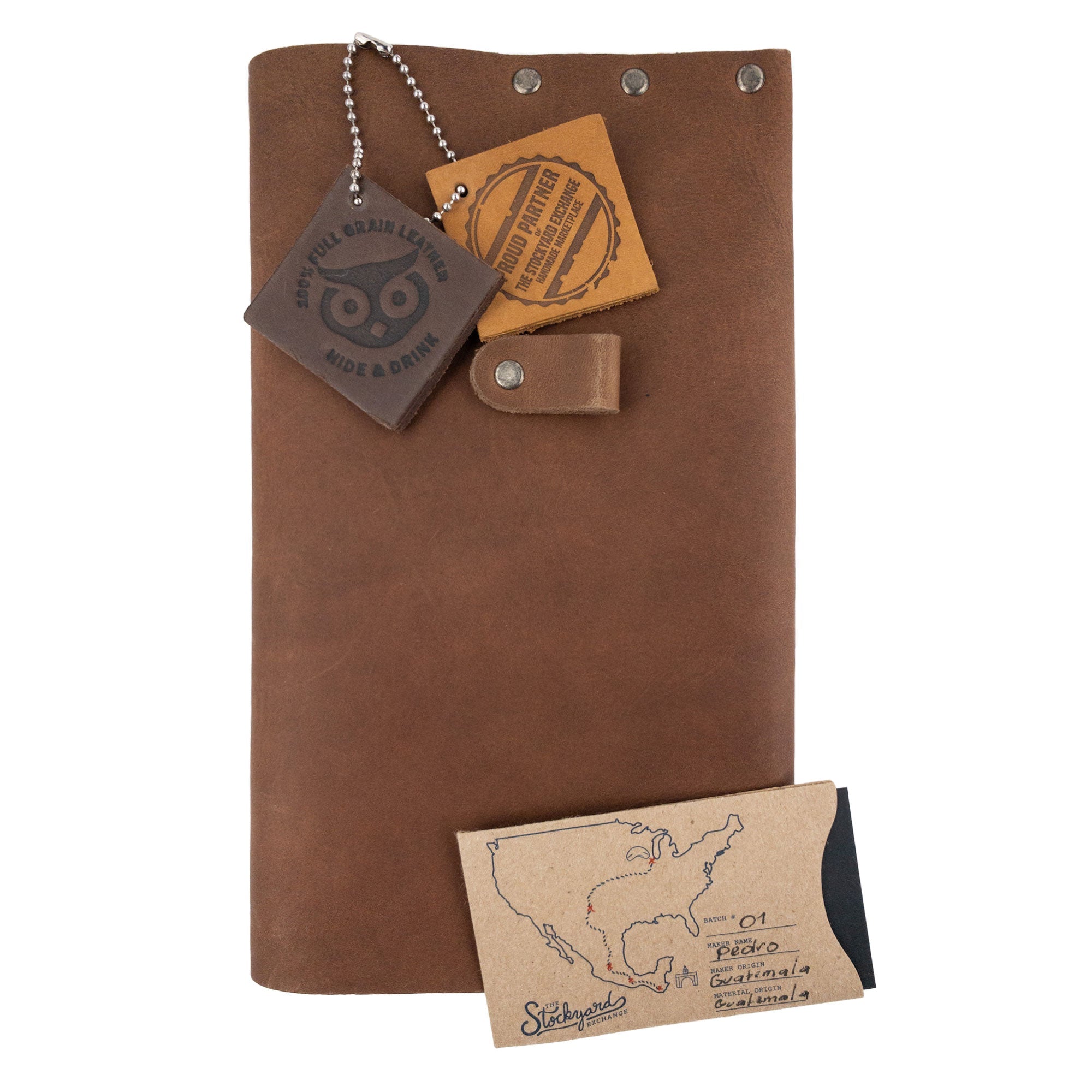 The Riveted Journal Cover (5 x 8.50 in.) by Hide & Drink displayed with care instructions and tags. This artisan handmade product showcases full grain leather and embodies the vintage style typical of small batch production from La Antigua Guatemala and Oaxaca Mexico.