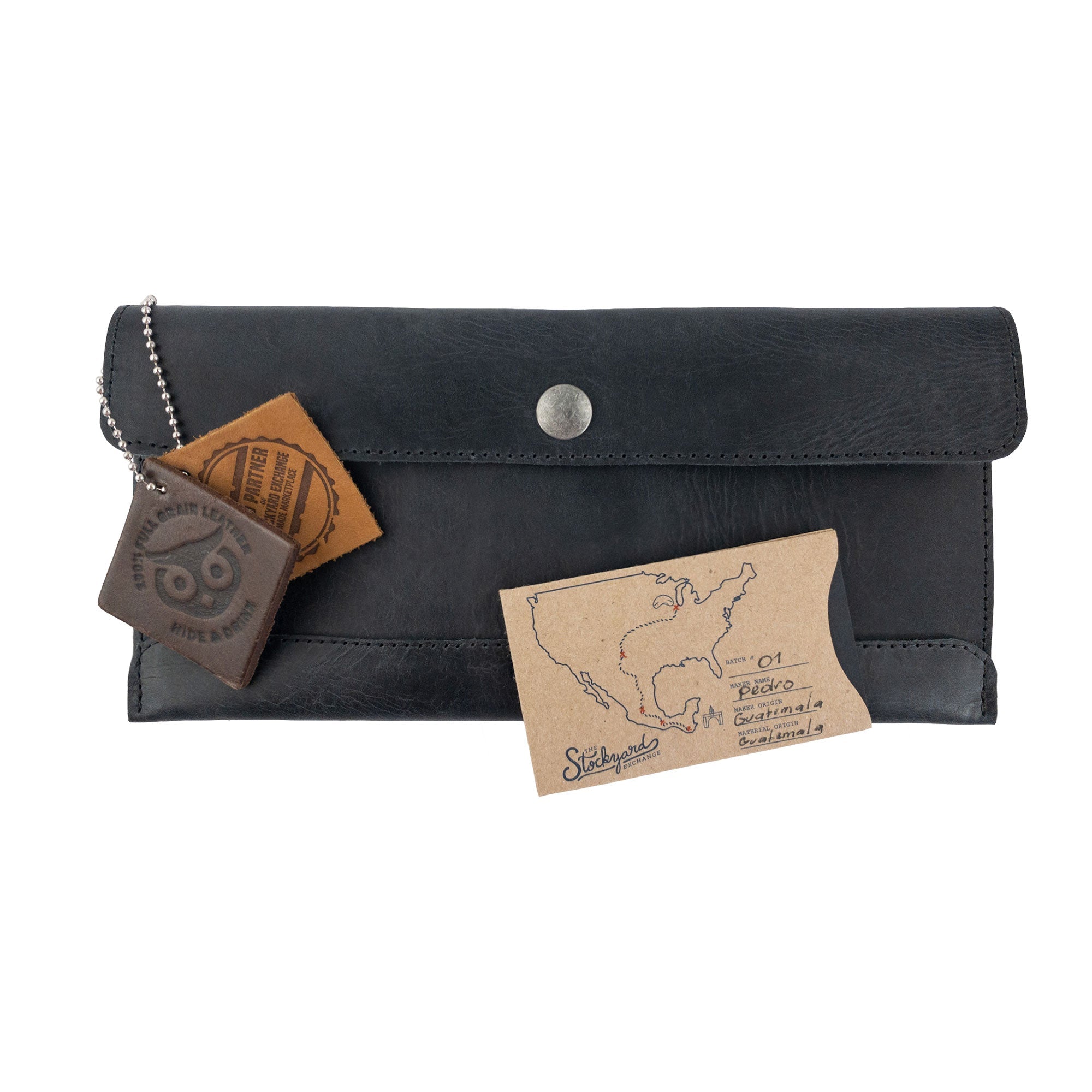 A charming display of Hide & Drink's black Travel Hand Wallet with custom accessories, showcasing its Full Grain Leather design. This Travel Wallet illustrates Small Batch Production and artisan crafting in La Antigua Guatemala & Oaxaca Mexico.