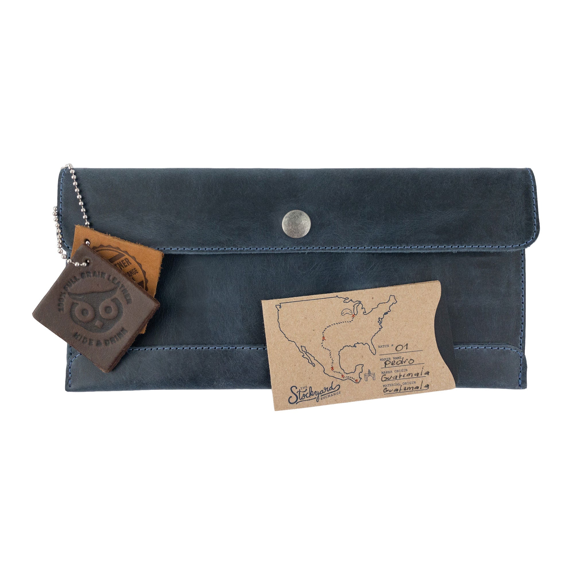 Hide & Drink's navy blue Travel Hand Wallet displayed with accessories, showcasing its sophisticated Full Grain Leather design. This classic Travel Wallet features Small Batch Production and artisan craftsmanship from La Antigua Guatemala & Oaxaca Mexico.
