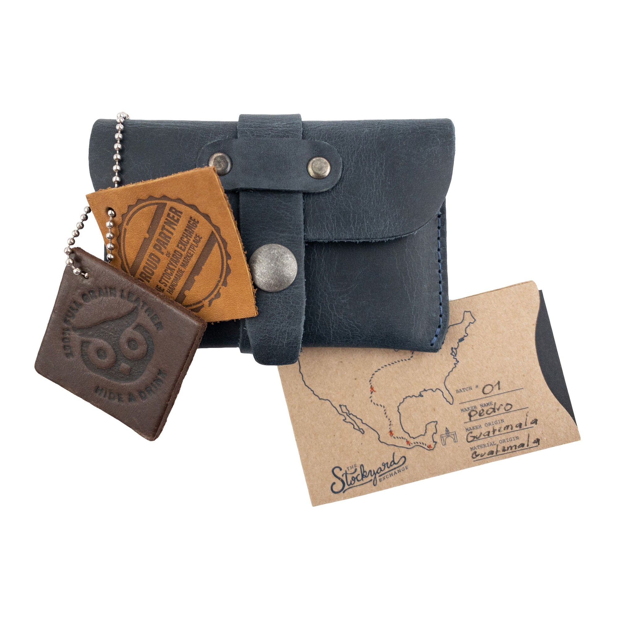 Hide & Drink's navy Credit Card Holder displayed with branded tags emphasizing its artisan quality. This Full Grain Leather wallet merges elegance and function, crafted with dedication in La Antigua Guatemala.