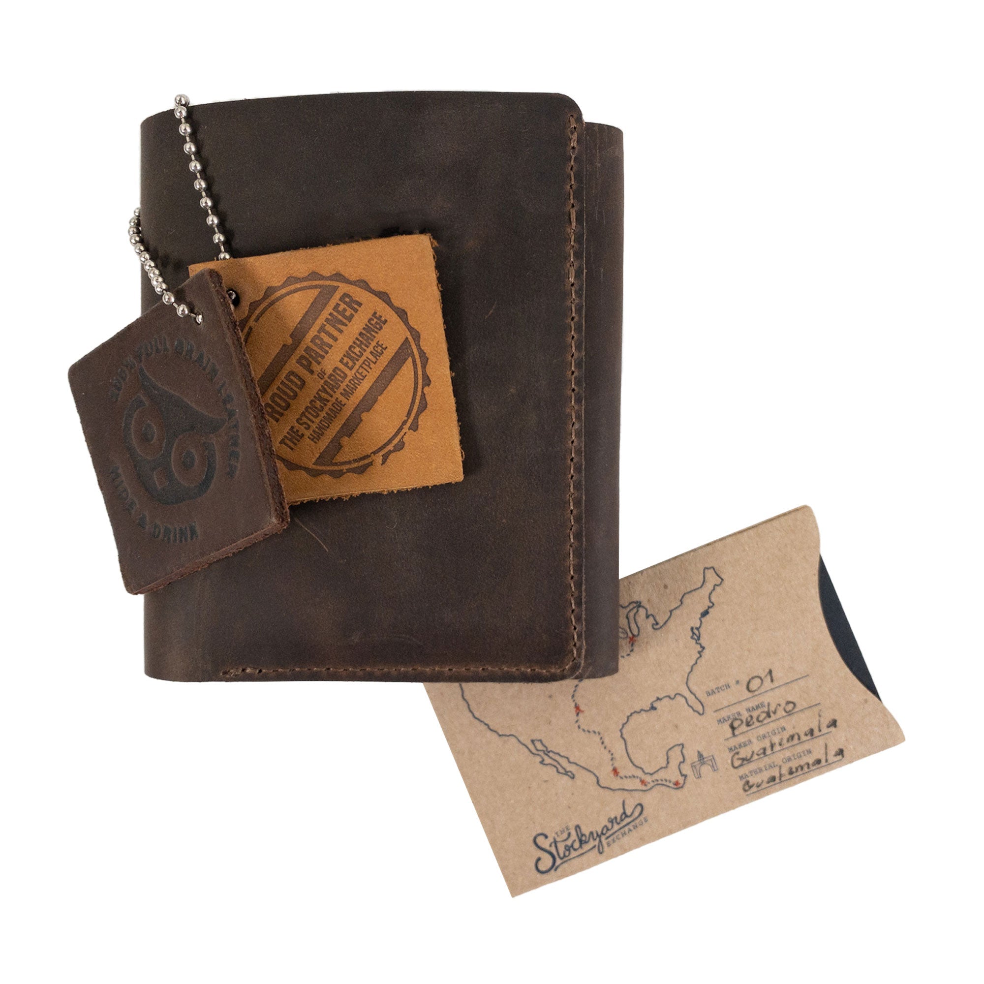 The Classic Trifold Wallet by Hide & Drink alongside a hand-cut tag, highlighting its heritage. Featuring Full Grain Leather, this wallet reflects Artisan, Small Batch Production craftsmanship from La Antigua Guatemala & Oaxaca, Mexico.