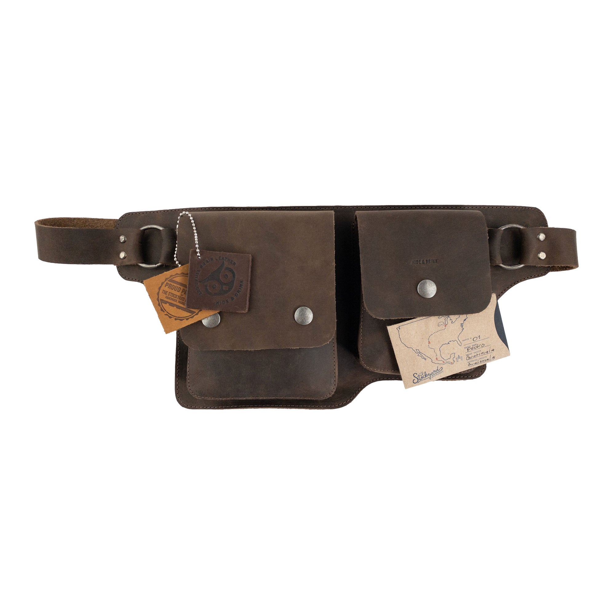 The Hide & Drink Rectangular Waist Bag displayed with tags, reflecting its artisanal quality and unique design. This Waist Bag with Adjustable Belt is made with premium Full Grain Leather, emphasizing its functionality as a tool holder for camping and its commitment to small batch production. Handmade in La Antigua Guatemala & Oaxaca Mexico, showcasing fine craftsmanship.