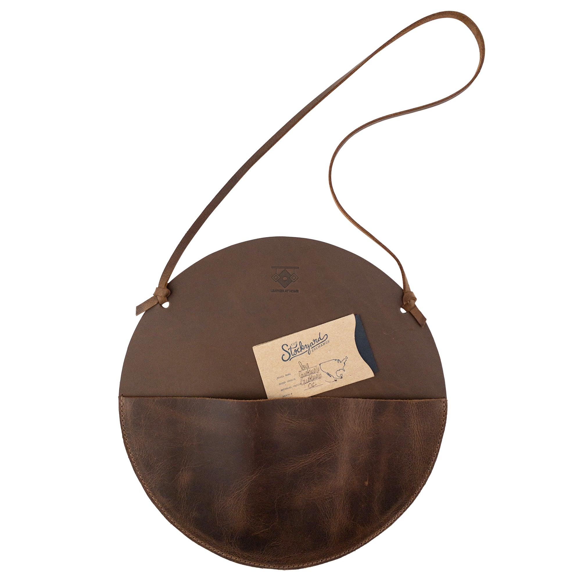 Leather At Home Circular Wall Hanger featuring a business card inside, showcasing its practicality as a mail storage solution. Handmade in La Antigua Guatemala, this item emphasizes quality with its full grain leather craftsmanship.