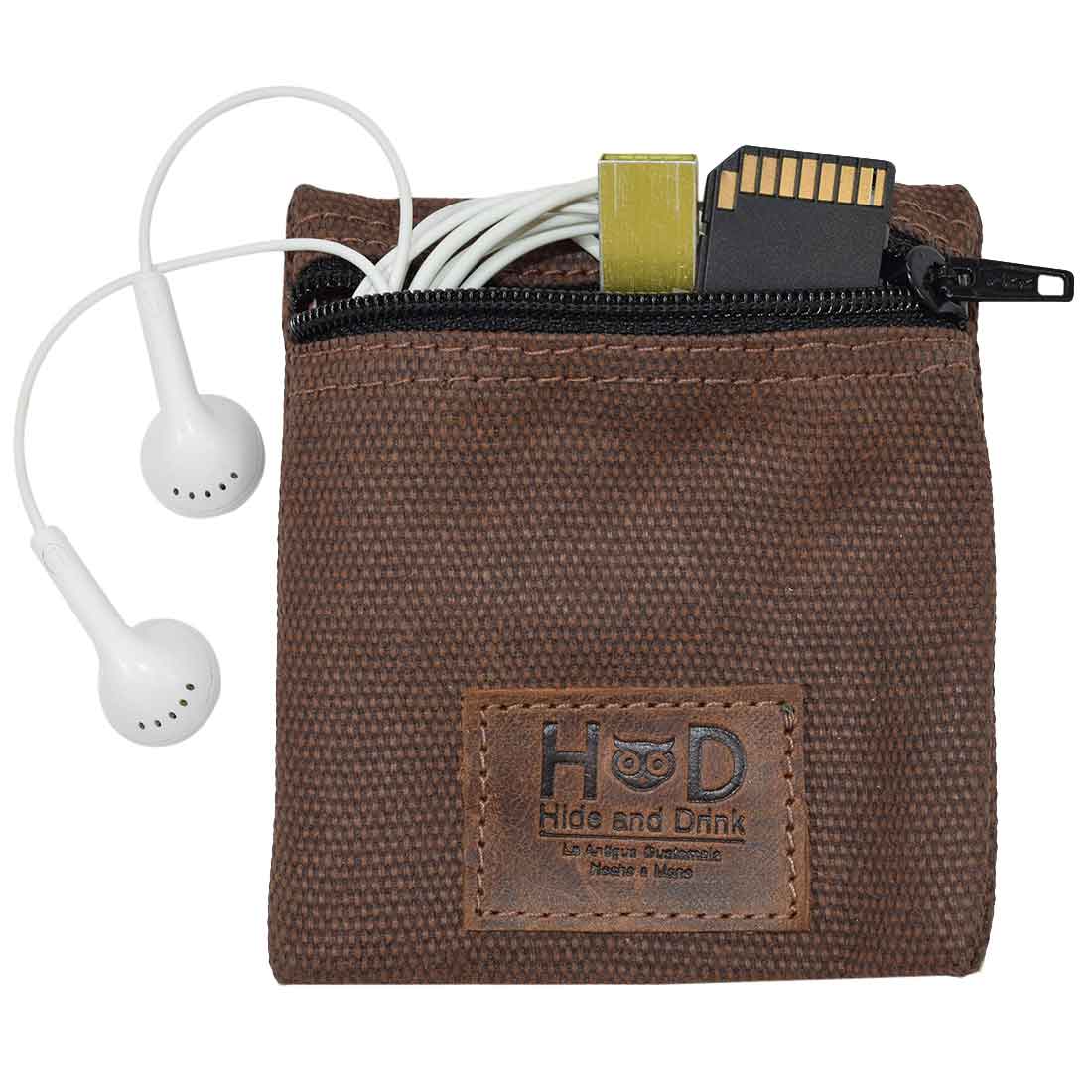 Hide & Drink Condom Pouch with earphones and a memory card, built from water resistant waxed canvas. This pocket purse serves as a practical tech organizer, ideal as a classic partner gift. Handmade in La Antigua Guatemala underscores artisan craftsmanship in small batch production.