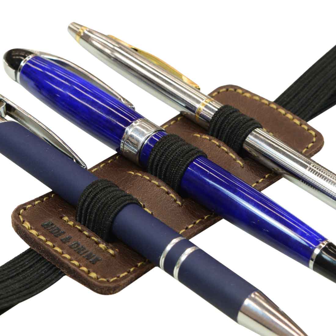 A detailed close-up of the pens and the leather construction of the Pen Holder W/Adjustable Band by Hide & Drink, showcasing its handmade quality. This practical accessory combines Full Grain Leather with small batch production for a unique touch.