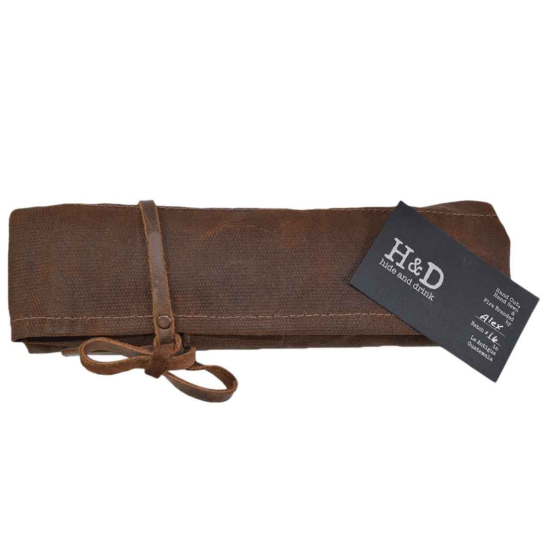 Hide & Drink's Wrench Roll (11 Pockets) rolled up, demonstrating a compact and portable design perfect for carrying tools. This Wrench Tool Roll is an essential hanging storage option for craftsmen. Made from durable waxed canvas, it serves as a rustic organizer with hand cut and hand sewn details, showcasing small batch production, and is fire branded, artisan crafted in La Antigua Guatemala & Oaxaca Mexico.